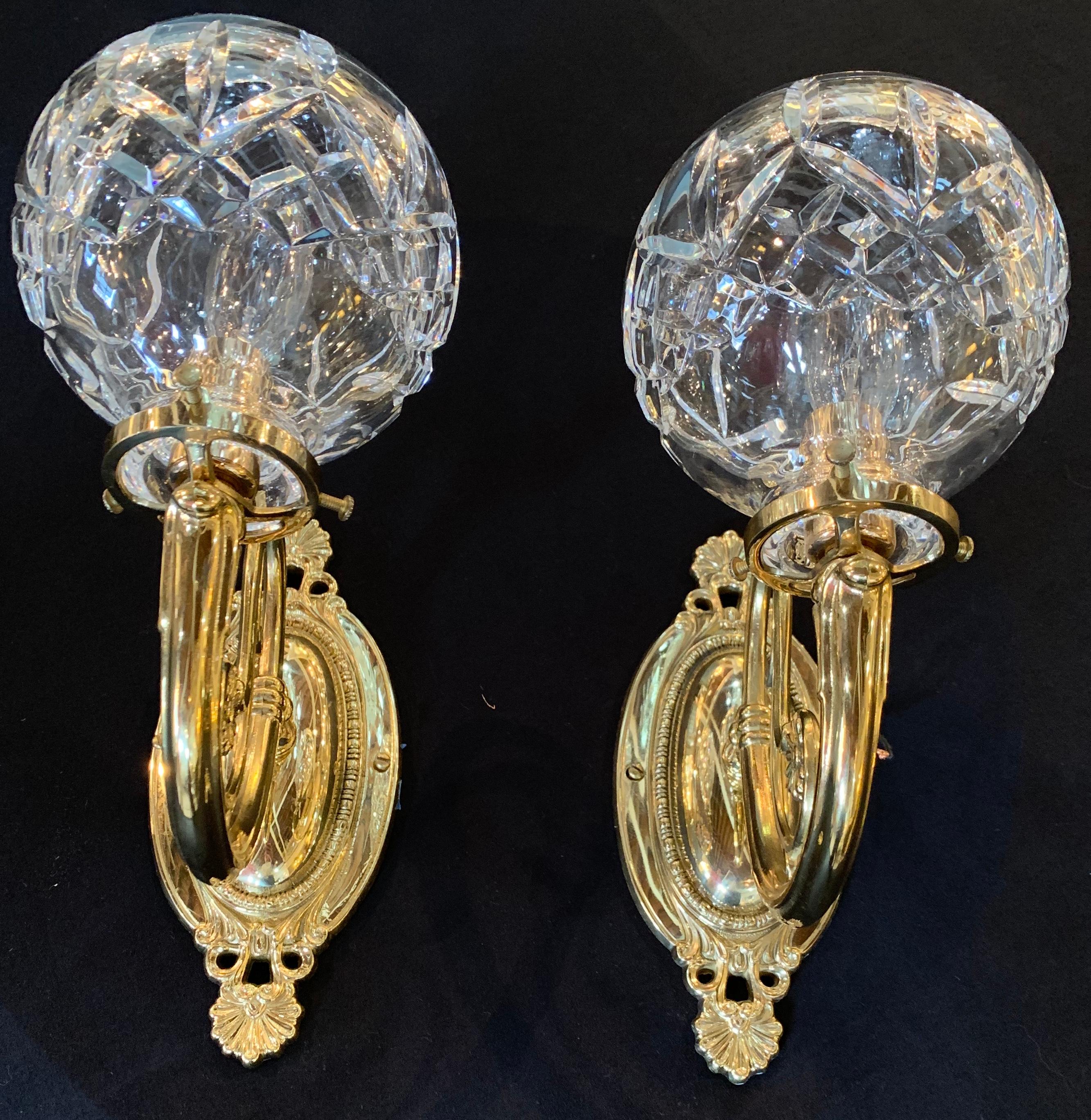 Pair of Hollywood Regency style Waterford brass and crystal single light wall sconces on brass back plates.