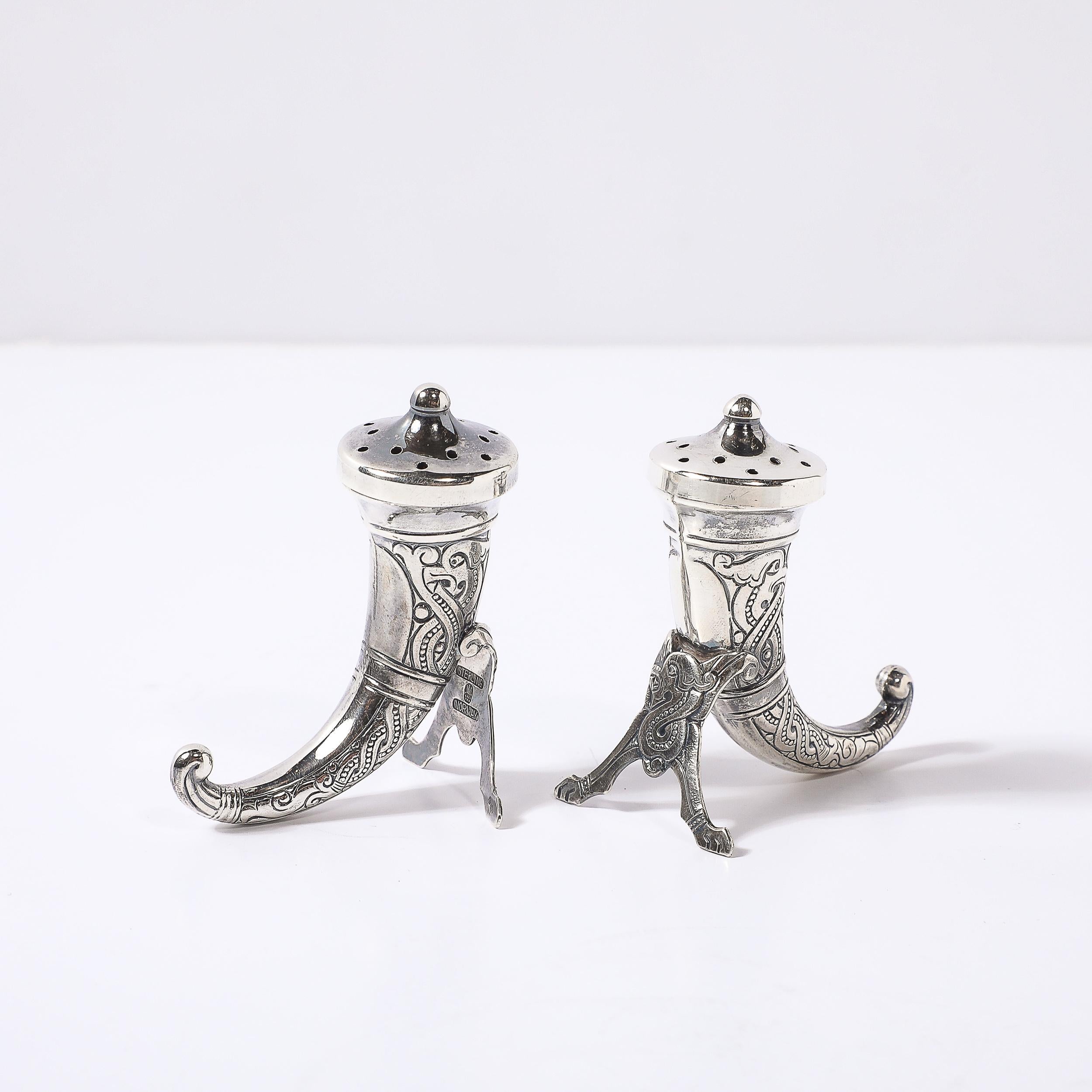 Cette paire de salières et de poivrières, conçue par le célèbre orfèvre norvégien Theodore Olsens, témoigne de l'élégance et du savoir-faire unique de l'artisanat scandinave. Fabriqués vers 1930, ces shakers sont façonnés en forme de cornes,