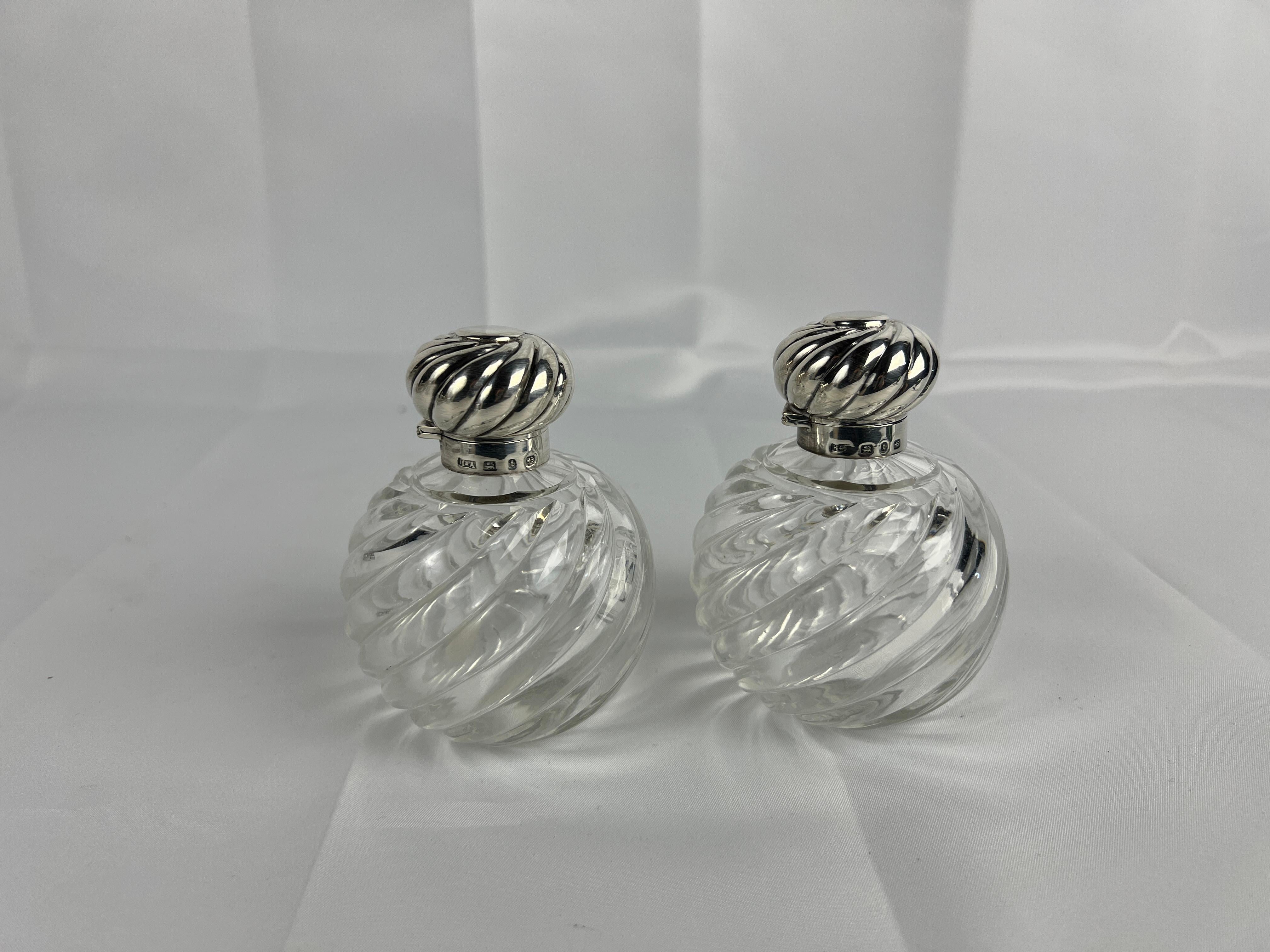 Este exquisito par de frascos de perfume de Horton & Allday, fabricados en 1893, combina la elegancia del diseño victoriano con una artesanía excepcional. Los cuerpos de cristal arremolinado presentan intrincados motivos soplados a mano que crean un