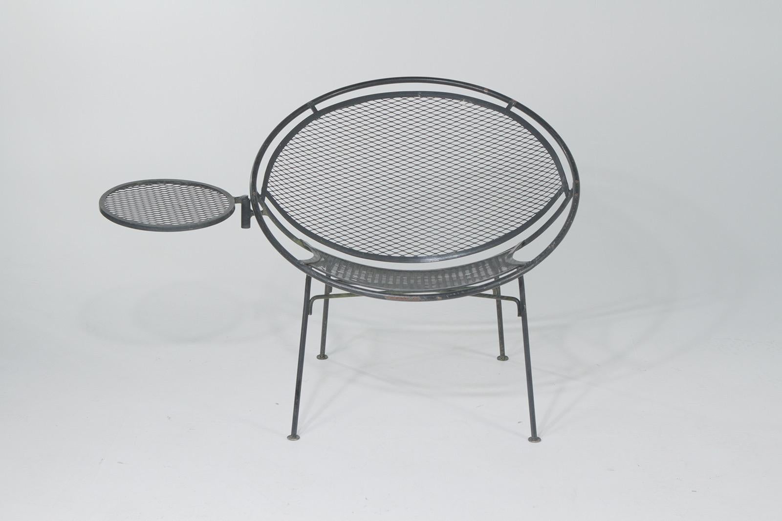 Stylishly shaped Mid-Century Modern wrought iron garden chairs by John Salterini having a 12 inch round cool drinks table that attaches to either chair.