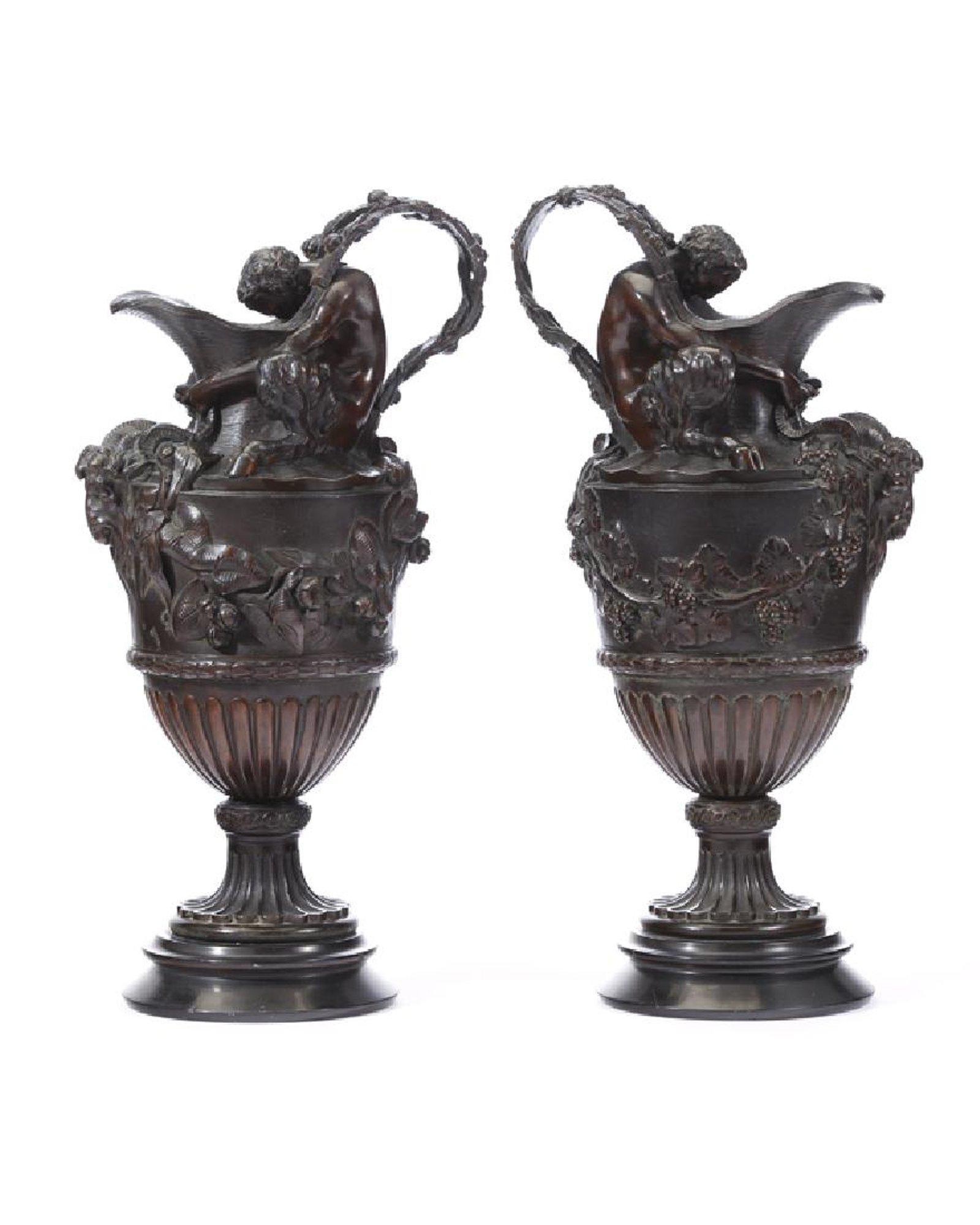 Exquisite pair of 19th century French patinated bronze urn ewers with figures. After Claude-Michel Clodion.

Each finely detailed ewer is surmounted by a seated Satyre embracing the neck, over a grotesque goat mask with intricate grape vine swags,