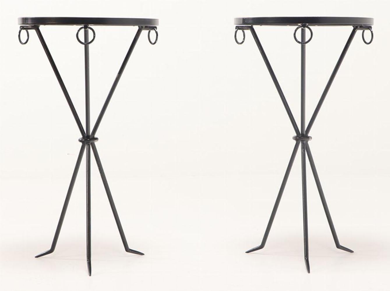 A pair of iron drinks tables with round parchment covered tops and ring decorated apron supported by an iron tripartite base.