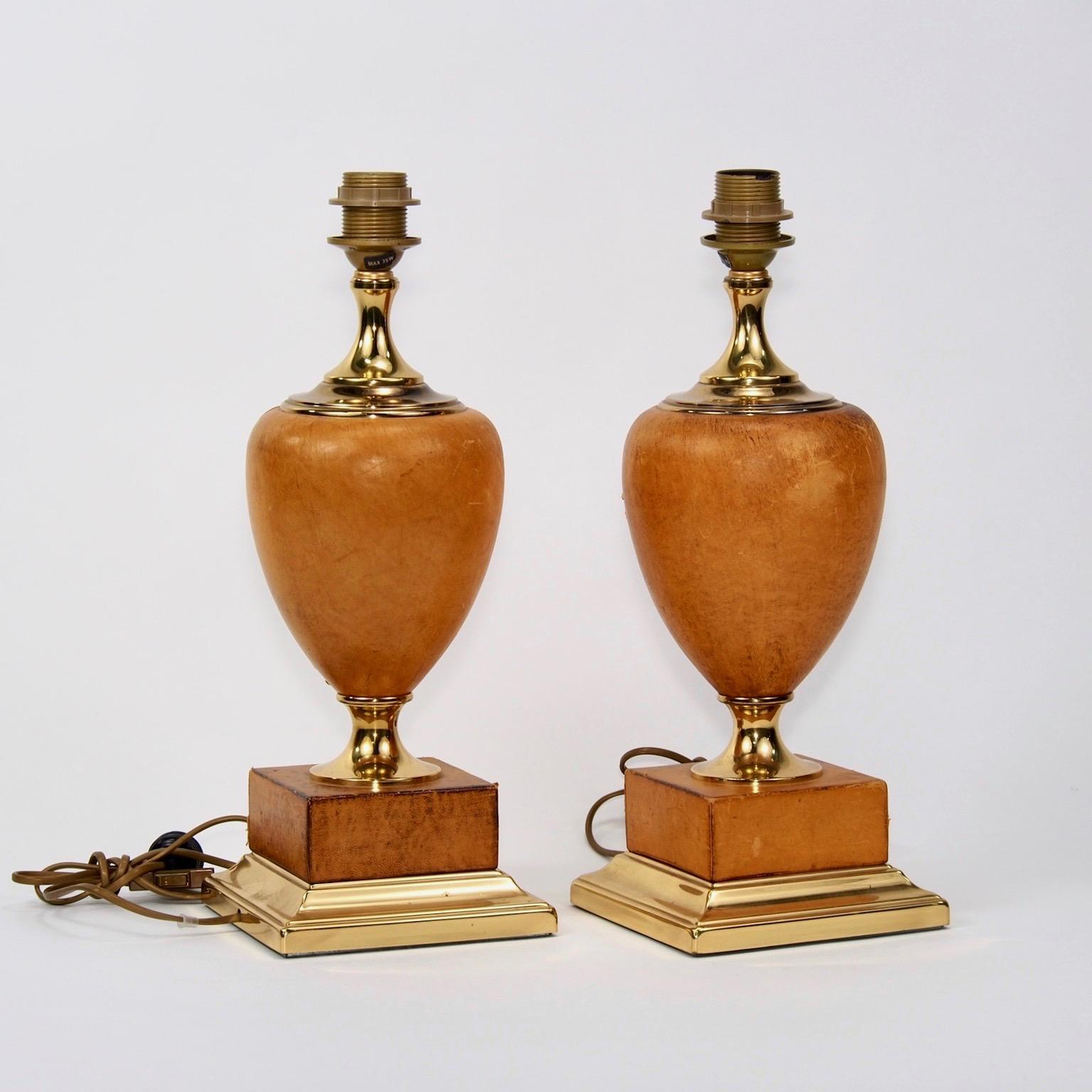 Found in Italy, this pair of leather covered and brass lamps date from 1940. Lamps feature leather-covered base mounted on polished brass pedestals, brass hardware and Classic urn-shaped leather-covered bodies with single standard sized sockets. New