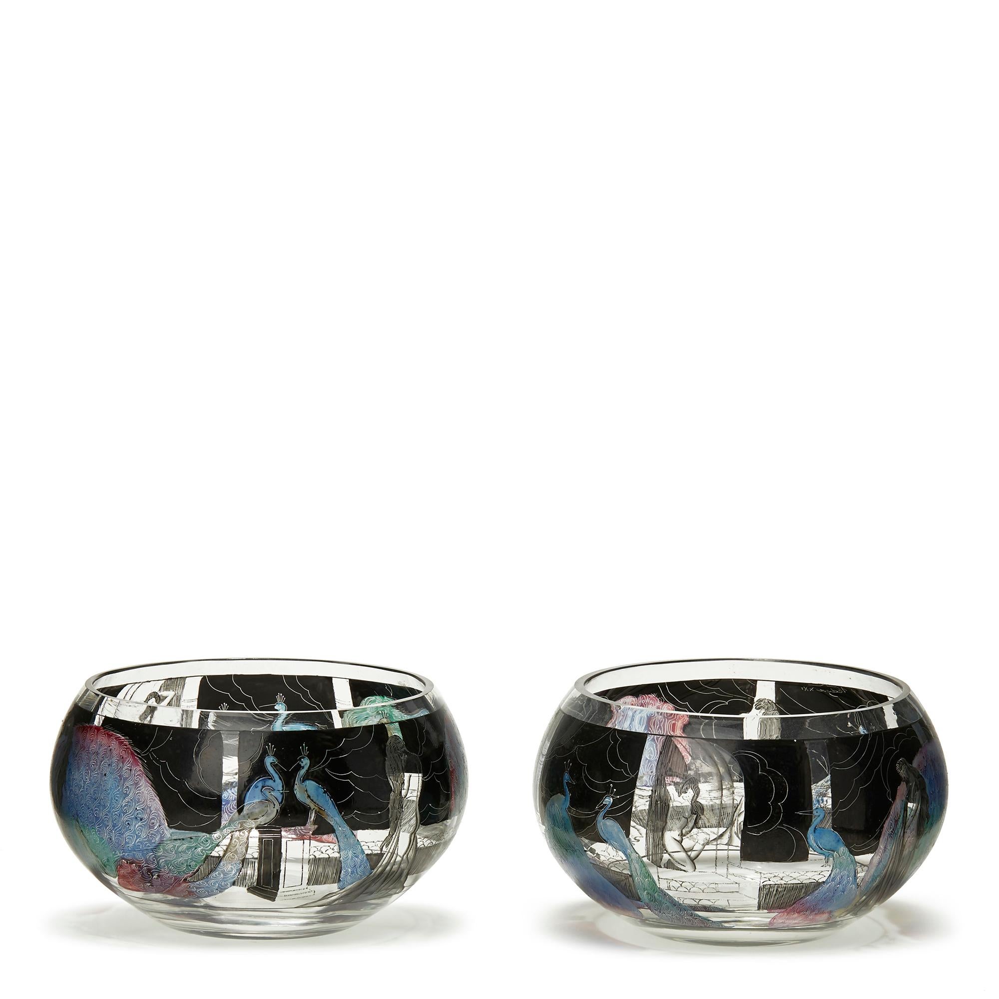 A stylish pair of Art Deco Vedar clear glass bowls hand enamelled with nude female figures and peacocks within a garden setting coloured and set within a black continuous landscape ground. The bowls were made by Vetri d'Arte (Vedar) which was