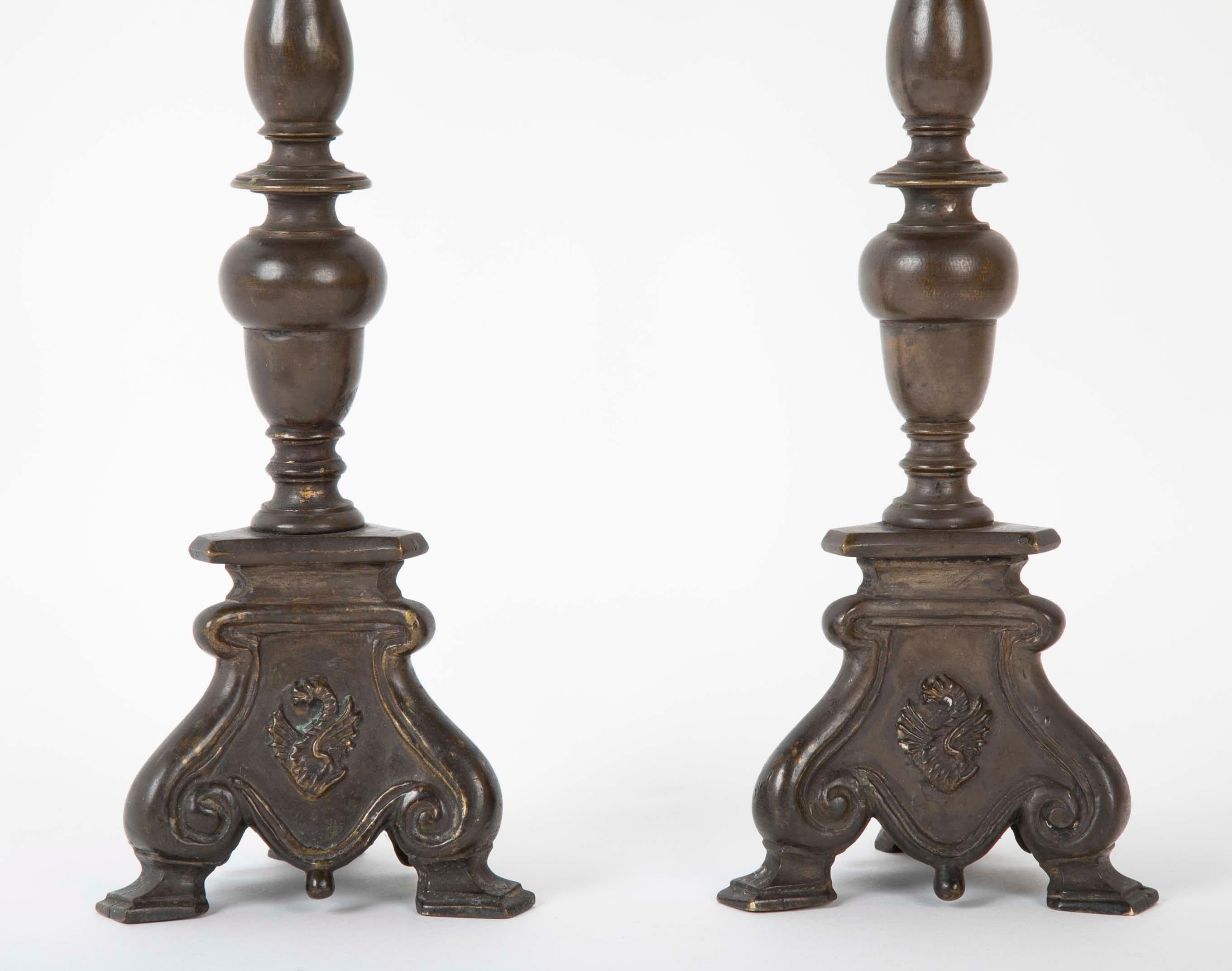 Pair of bronze pricket sticks with an unusual dragon motif on the base. Each with a turned shaft supported by a tripod footed base, all three side decorated with a raised winged dragon. Italian, late 17th or early 18th century. A rich dark patina.