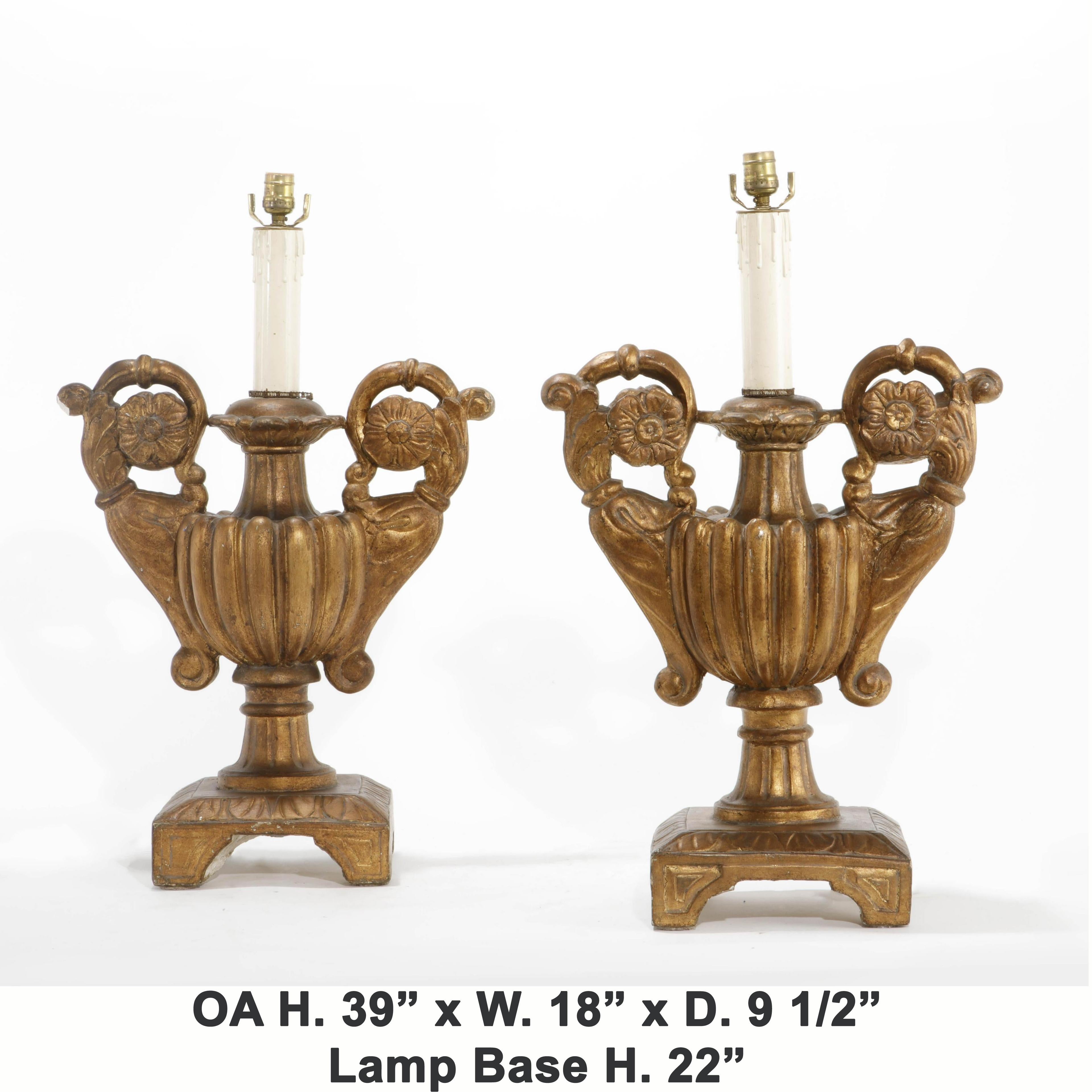 Attractive pair of Italian Baroque style carved giltwood urns lamps, 
mid-20th century.

Beautifully gilded Baroque style urns mounted to lamps, with a carved gadrooned body, flanked by scrolling foliate inspired arms, ending in rosettes, raised
