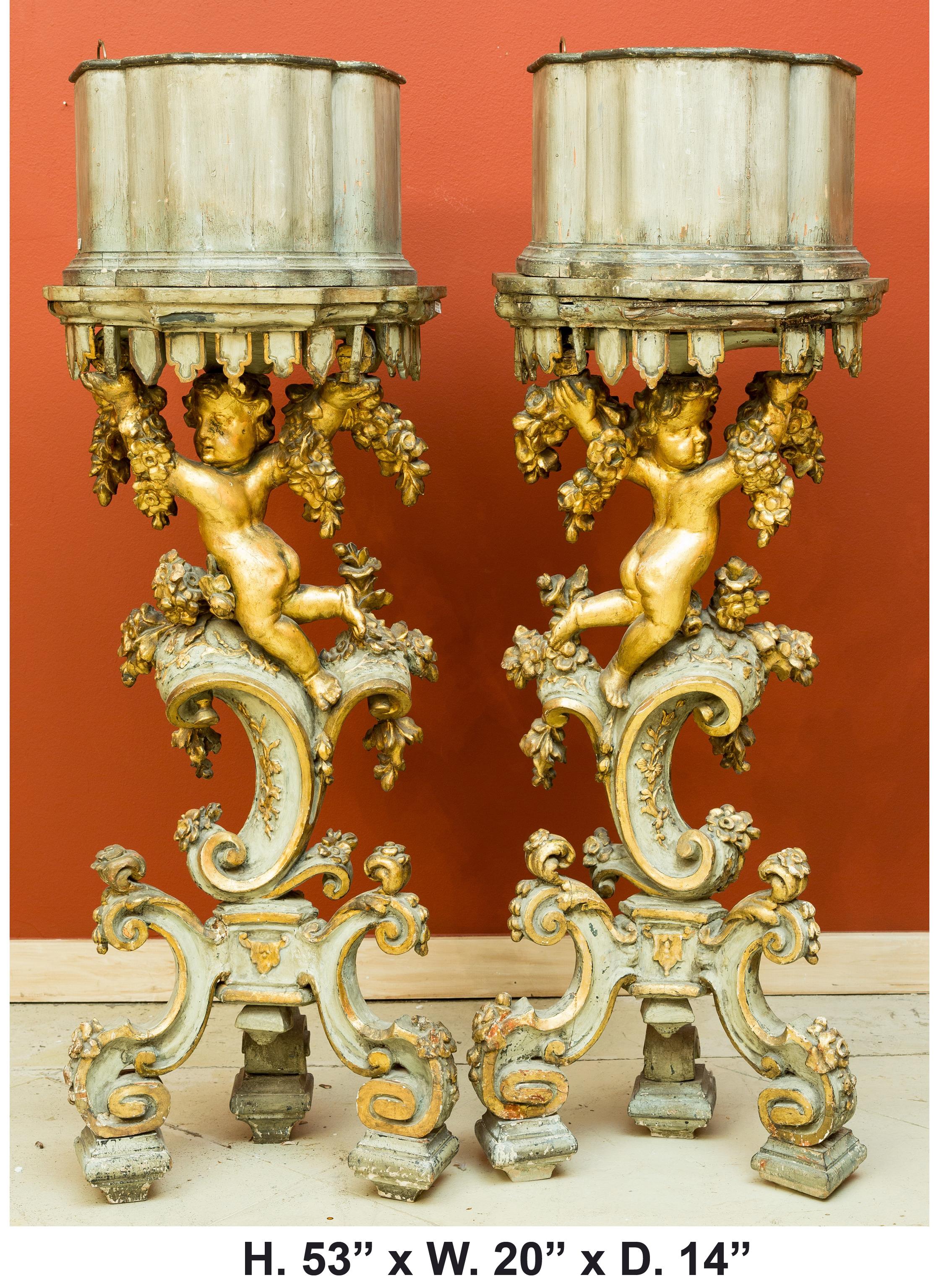 Attractive pair of Italian Baroque style jardinière pedestals, 19th century.
A shaped brass planter rests on top of a painted conforming platform, over a hand carved giltwood frolicking putti with foliate swags in each arm, raised on a parcel gilt