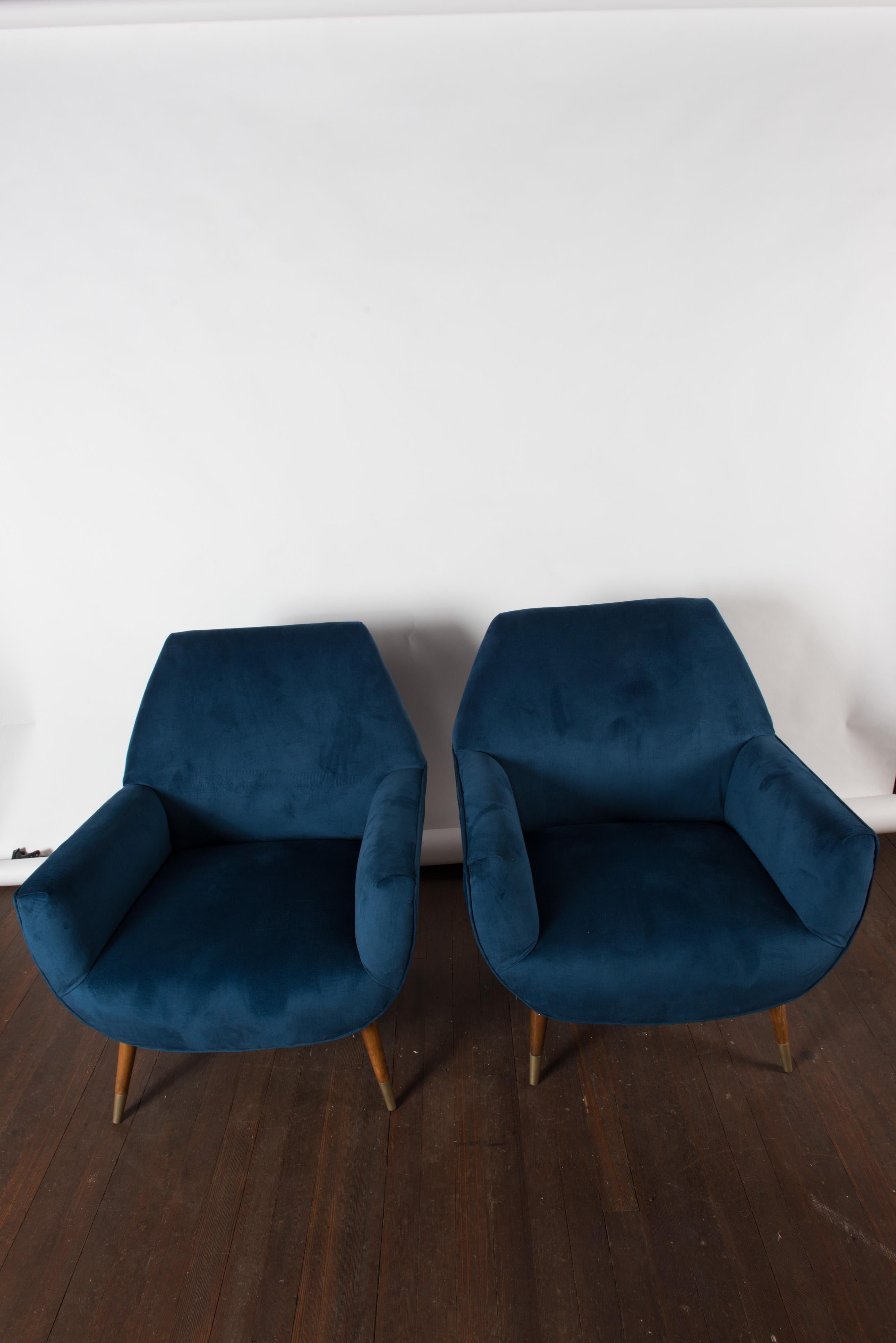 Newly upholstered in blue velvet, a pair of Mid-Century Modern Italian lounge chairs.
Wood legs with brass feet.
