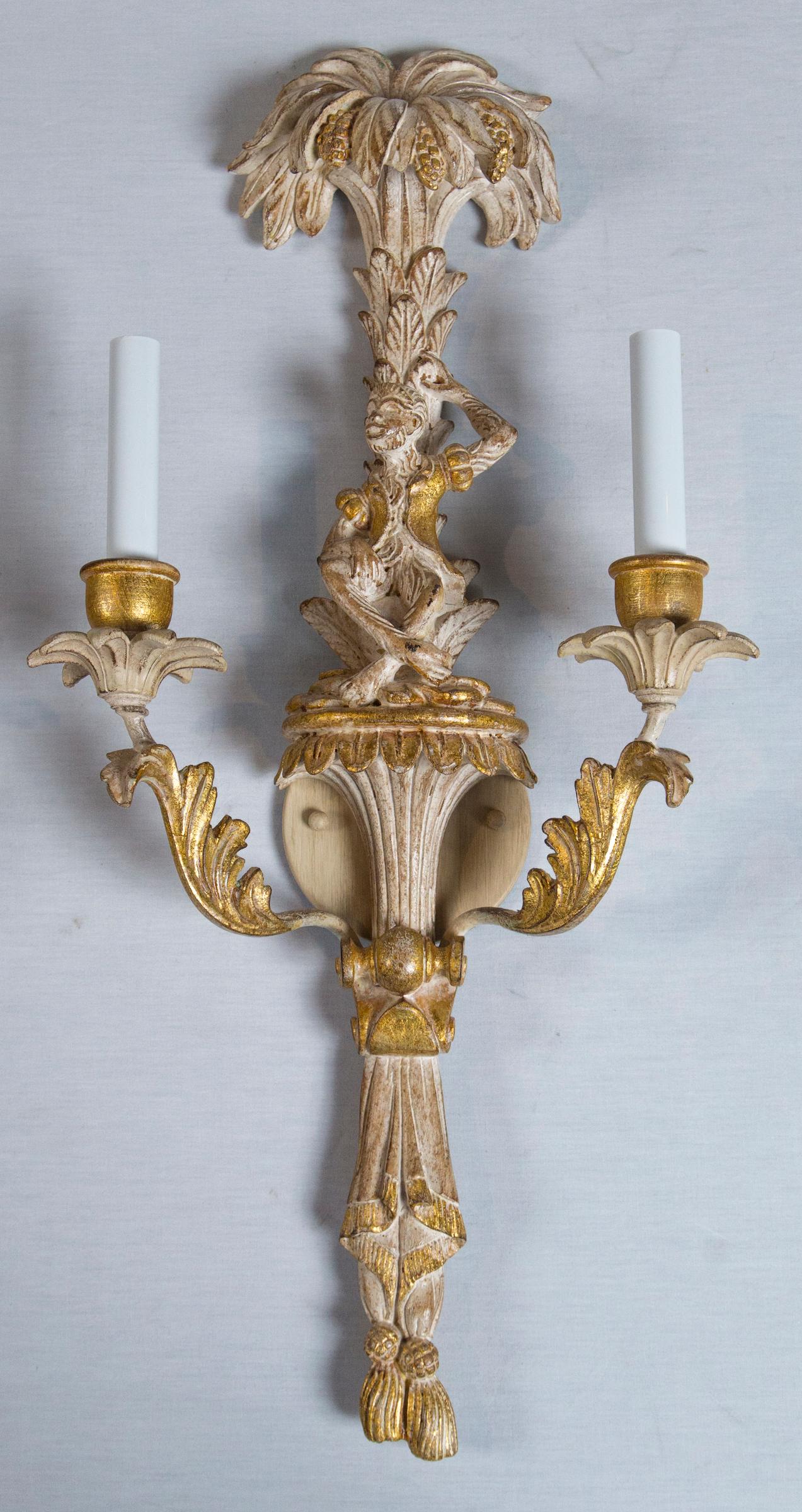 A whimsical pair of carved wood Italian chinoiserie sconces with monkeys and palms. These are new unused 1960s stock. The carved wood is lightly Cerused and gilded. Each sconce is wired for two chandelier bulbs.