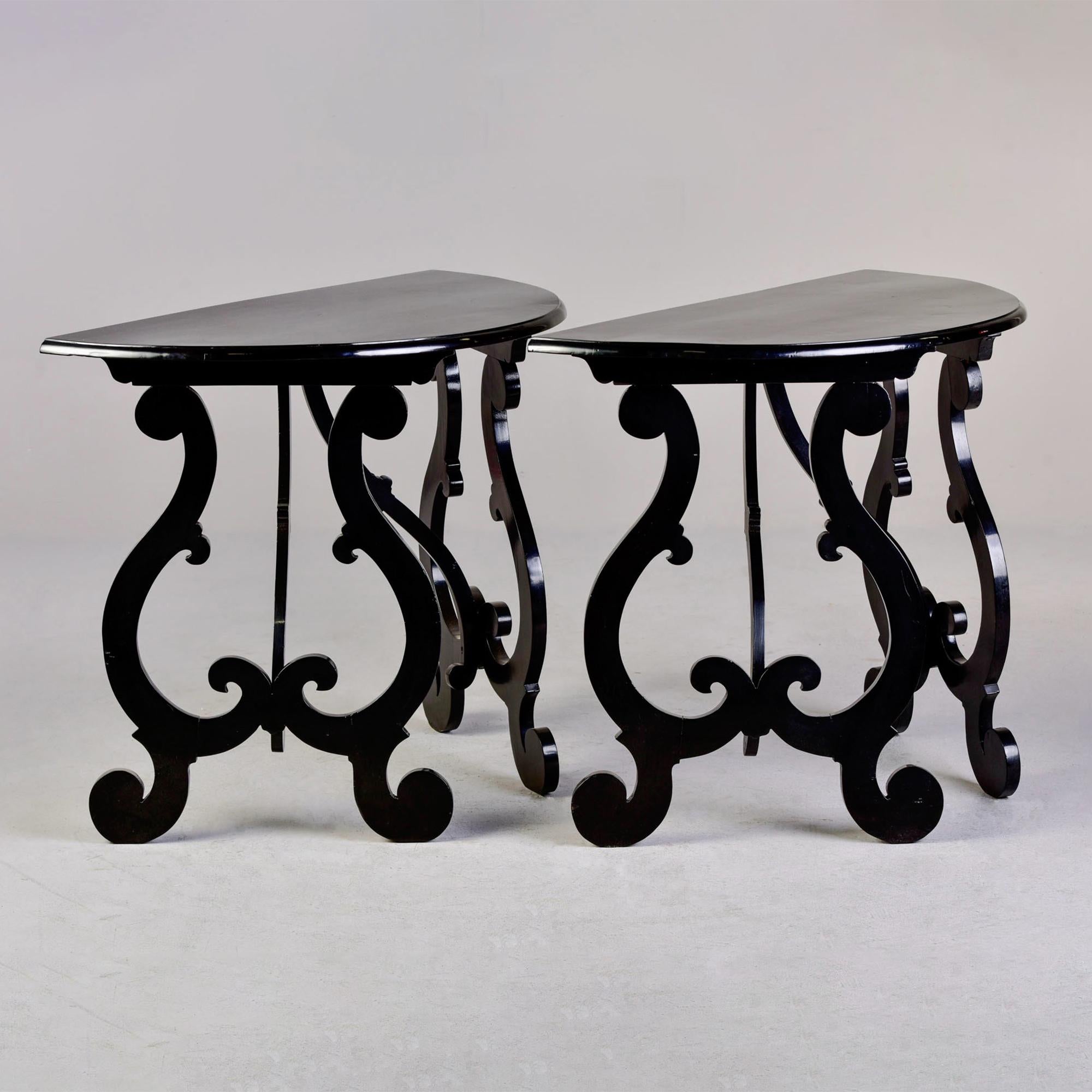 Circa 1920s pair of Italian walnut demi lune consoles with fancy, carved lyre legs and new, professional ebonised finish. Unknown maker. Sold and priced as a pair.