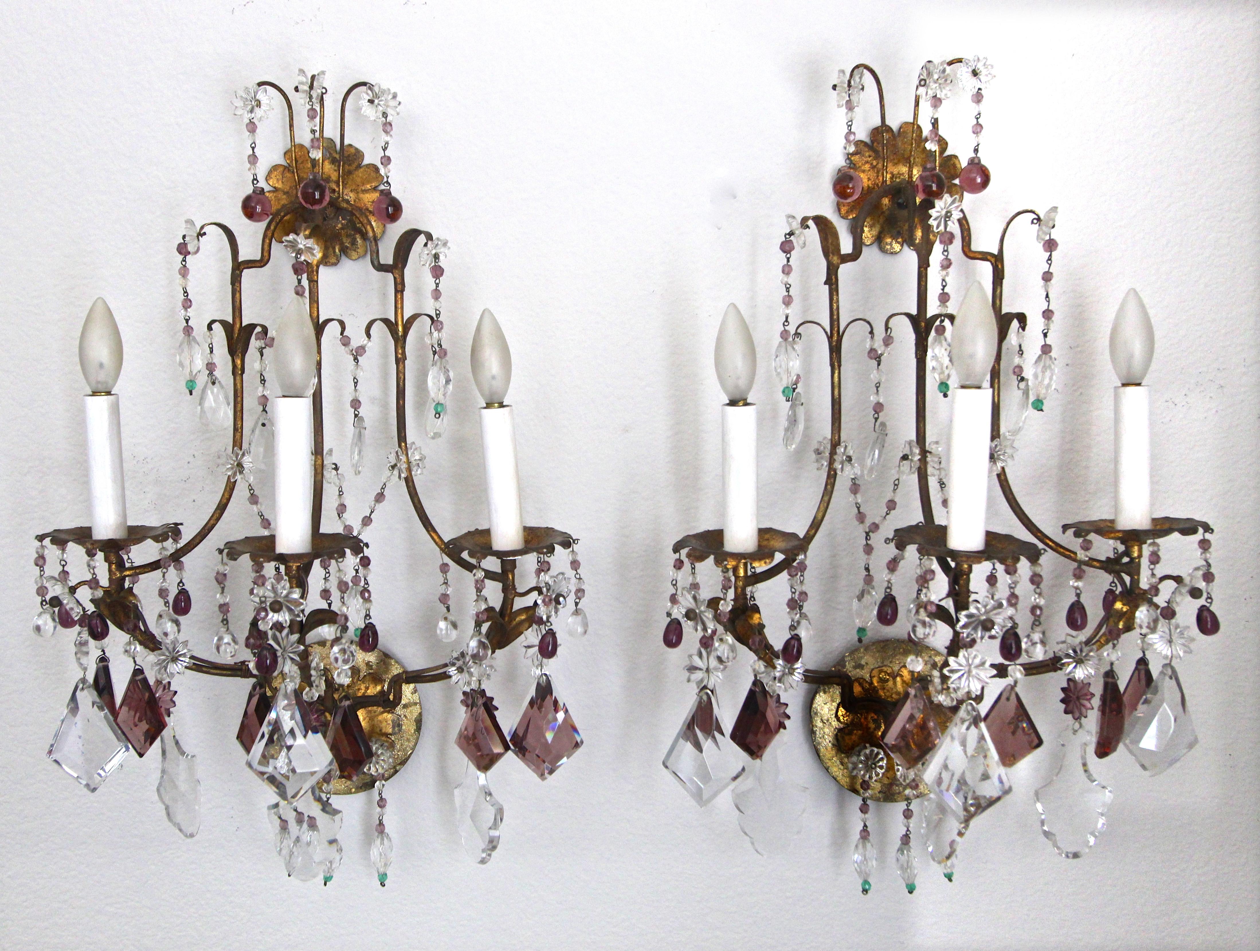 Pair of elegant 1940s gilt metal three-light wall sconces with clear and lavender crystals and beads. Each sconce uses 3 candelabra base bulbs. Newly wired. (Newer gilt finish style backplates added for US installation.).