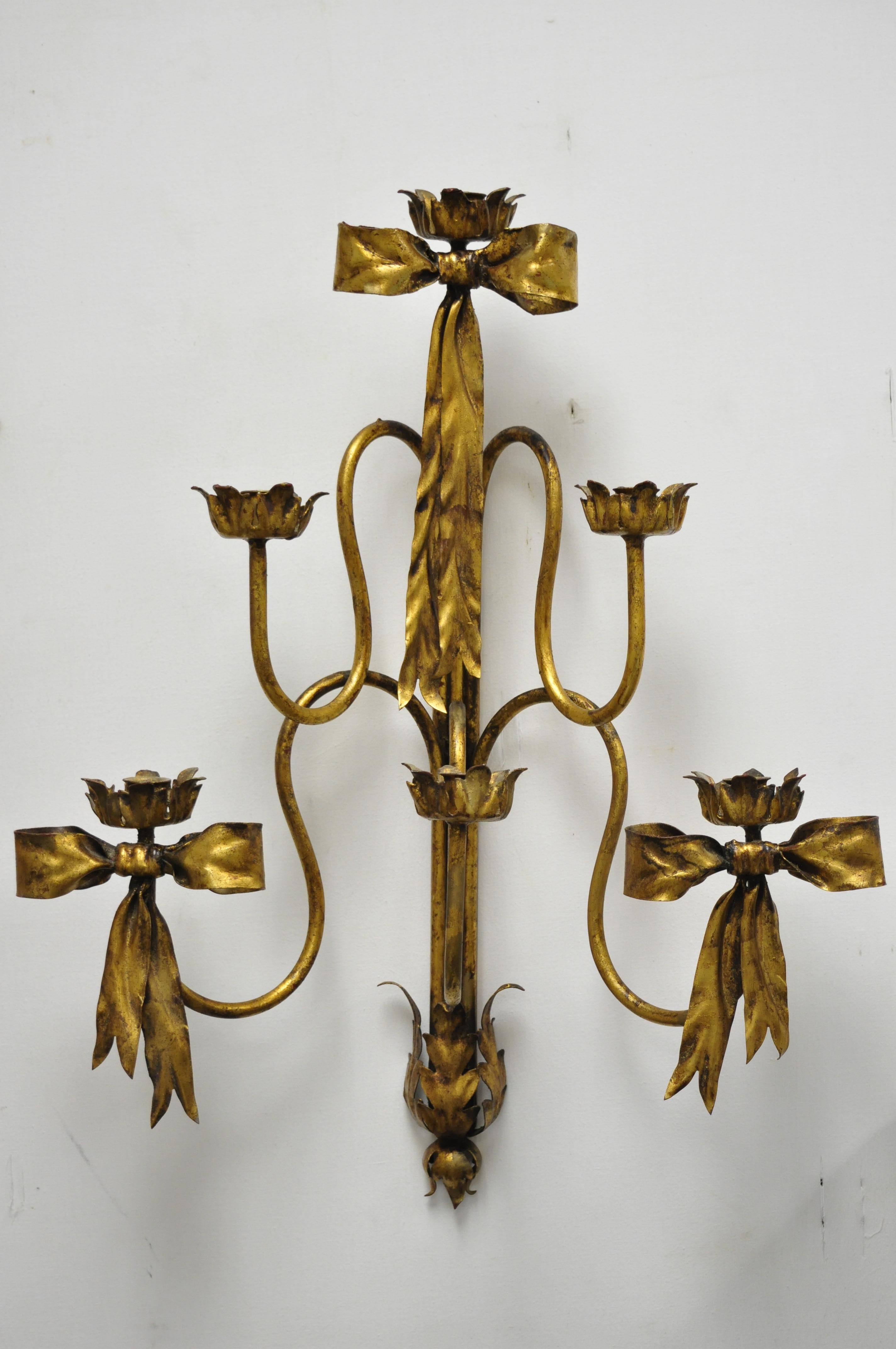 Pair of Italian Hollywood Regency gold iron bow form tole metal wall sconces candelabra. Items feature wrought iron frames, 6 arms, 6 candleholders, gold leaf finish, original label, very nice antique item, does not include candles, circa mid-20th