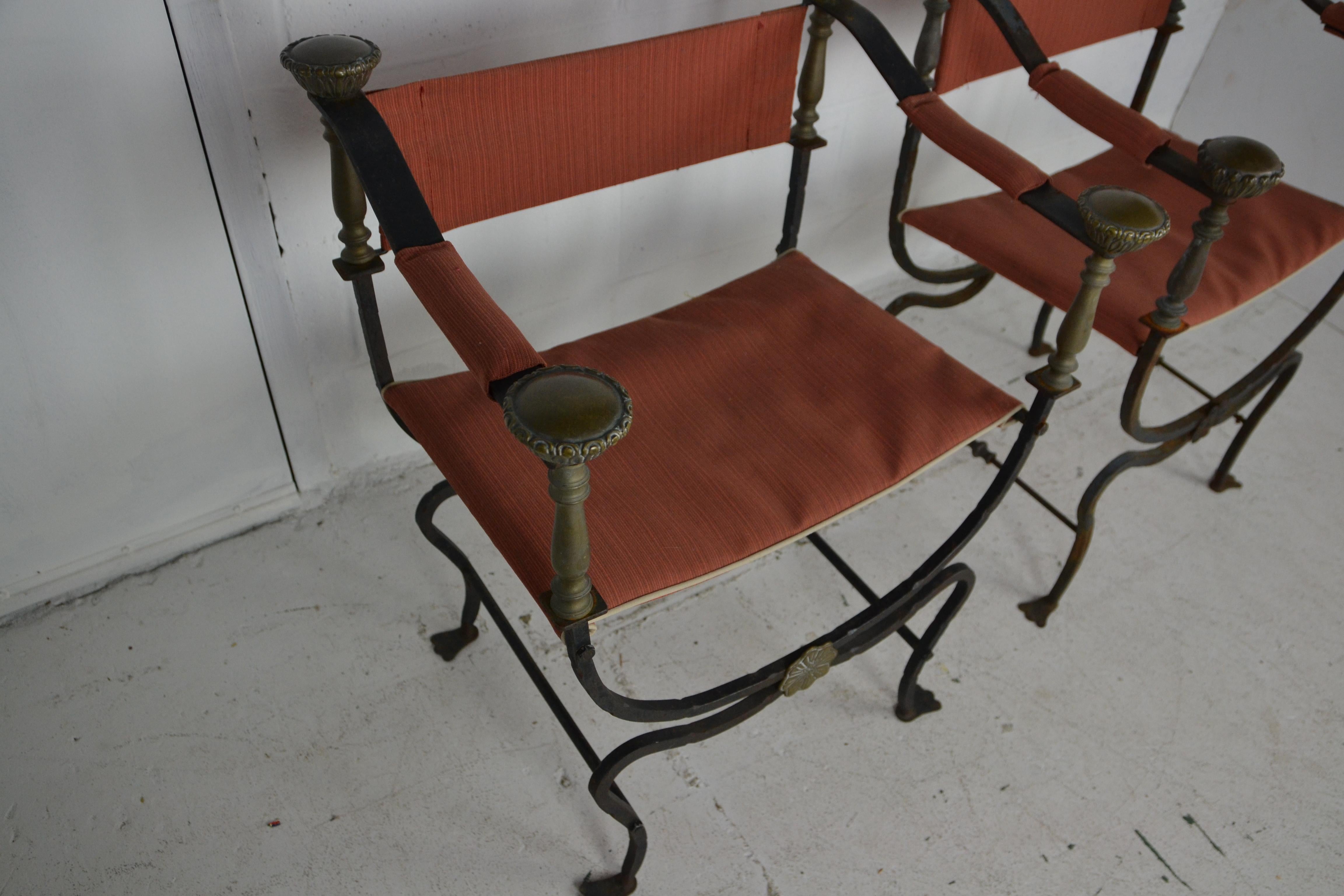 A pair of 1920s Italian iron and brass Savonarola chairs. Turned brass uprights topped with huge brass finials. Front of X-stretchers decorated with a steel floral medallion.