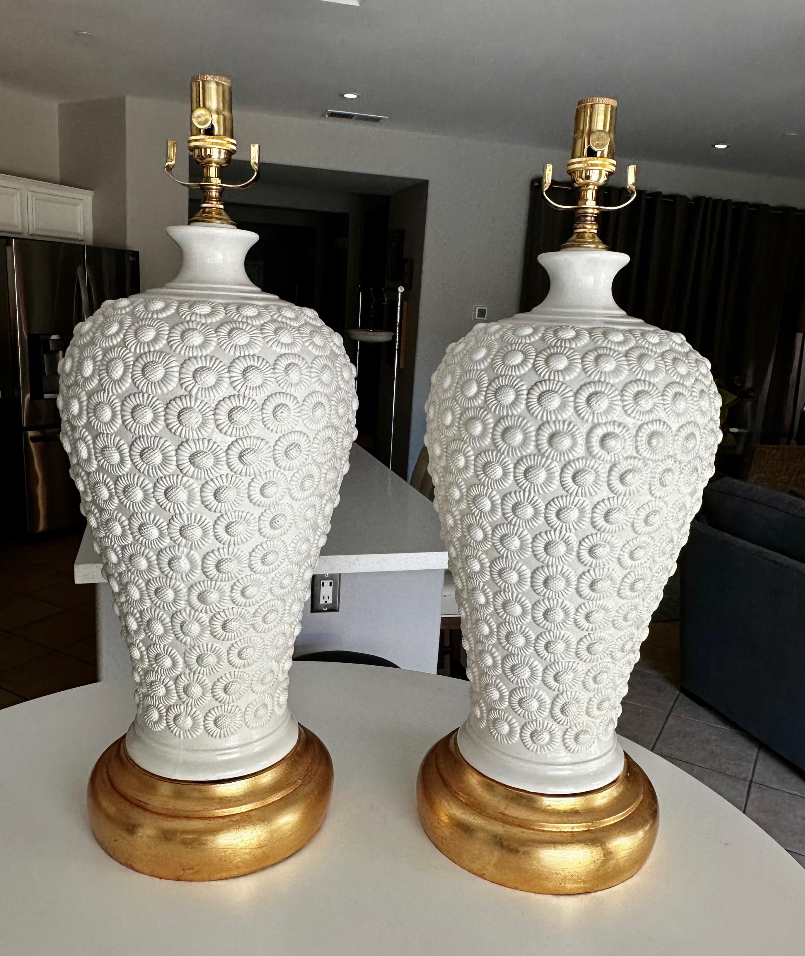 Pair of large white Italian porcelain table lamps with repeated daisy flower pattern throughout. Mounted on turned giltwood bases. Newly wired with new brass 3 way sockets and cords. Overall height top of socket 25