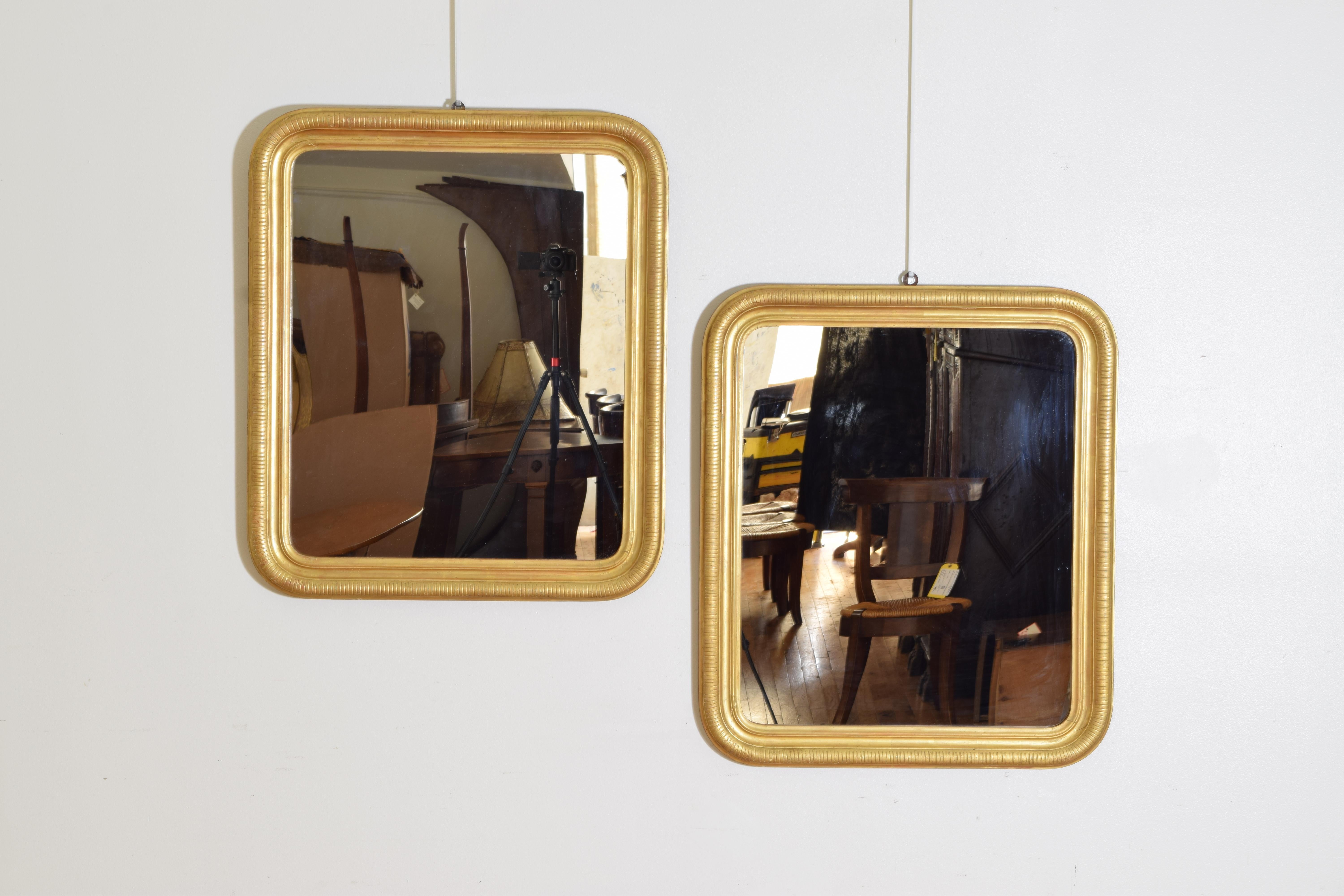Each mirror of rectangular form with rounded edges, a series of moldings make up the frames, the outermost with incised ribbing, the mirror plates modern