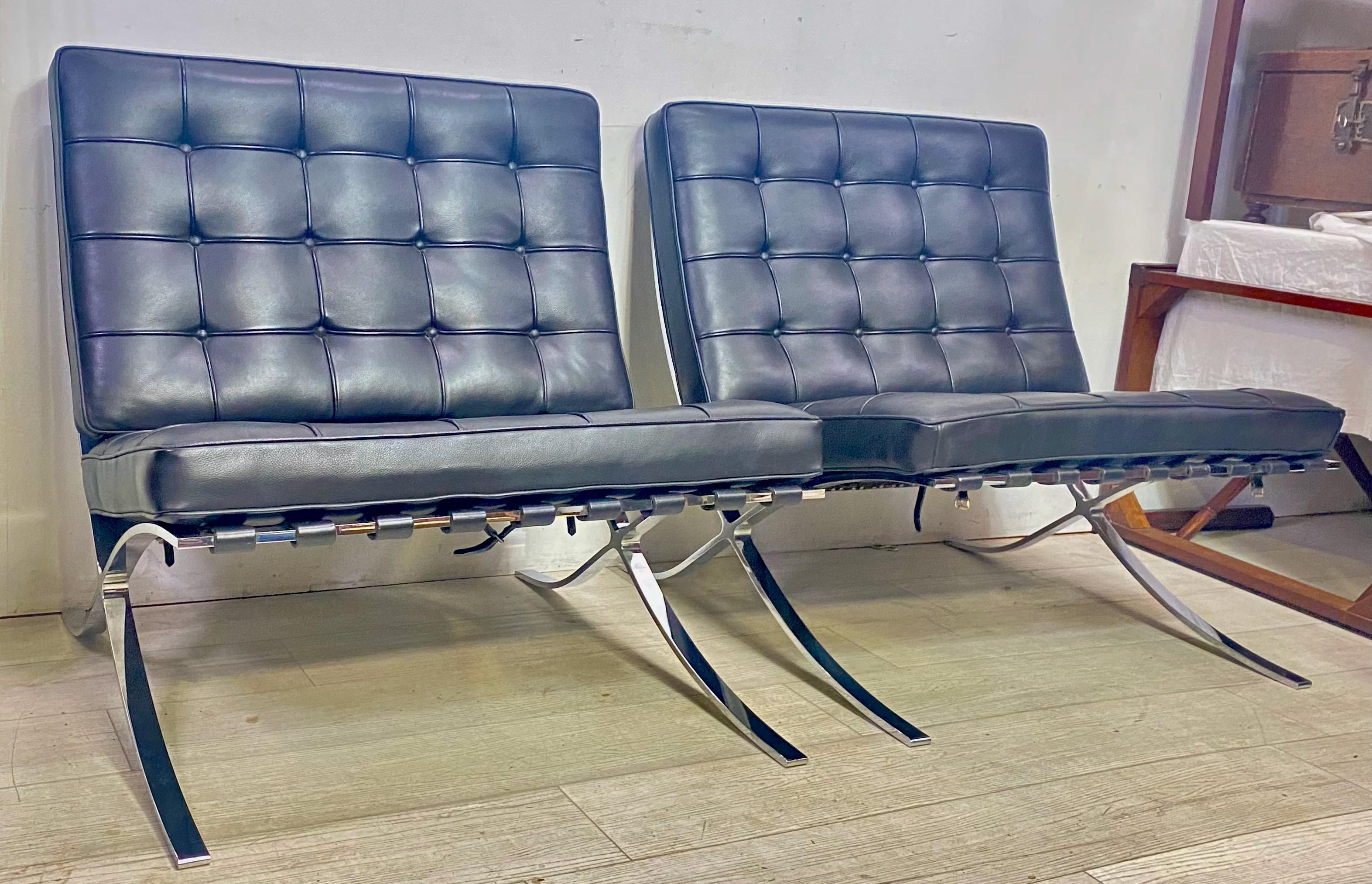 A pair of iconic “Barcelona” chairs in the style of Ludwig Mies van der Rohe. Initially created for the German Pavilion at the Barcelona exposition, each chair features a sturdy polished steel frame with leather slats supporting high quality black