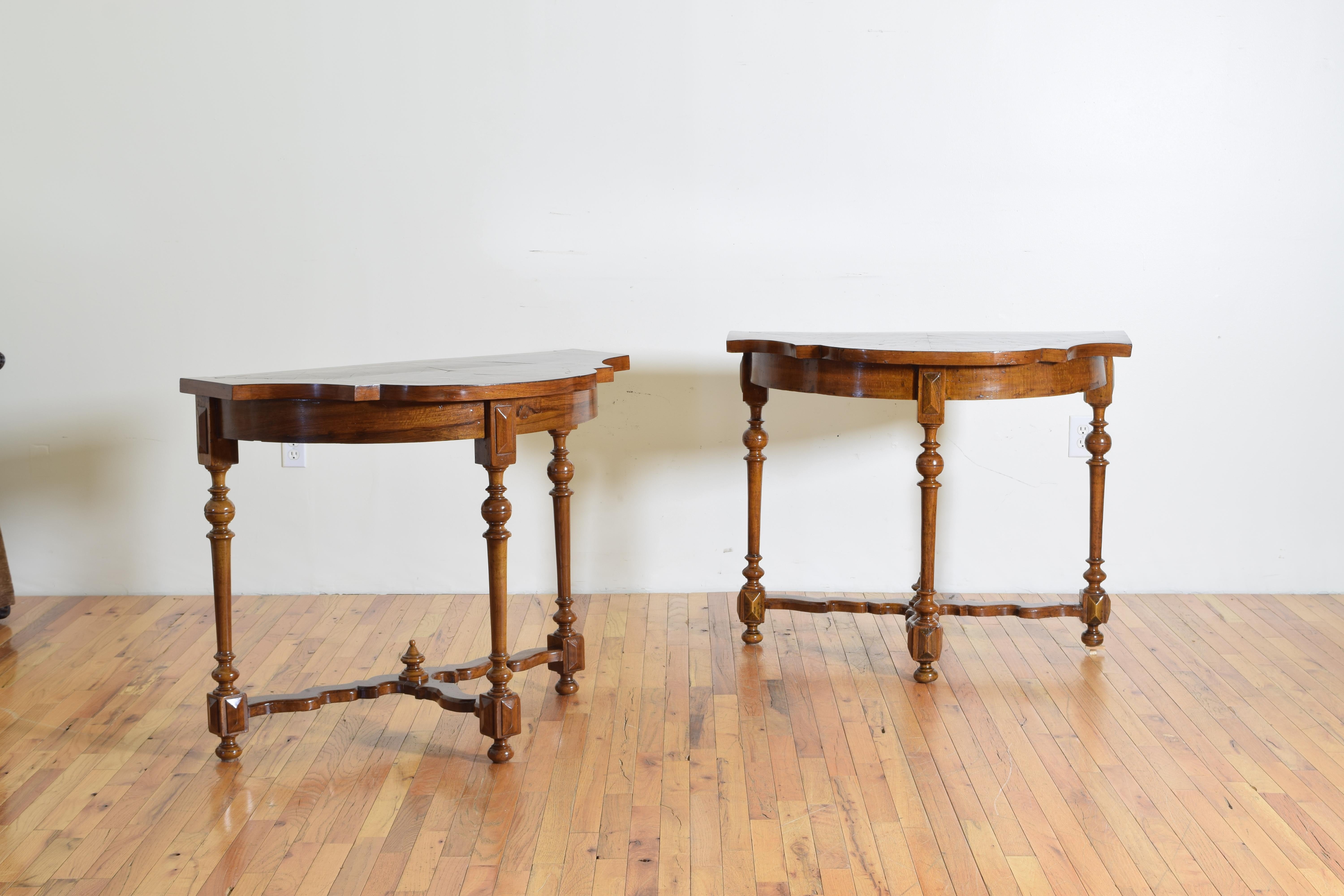 Having exaggerated bow shaped tops veneered in walnut banding and olivewood interiors, below the top are demilune shaped aprons, the turned legs with centered medallions at their tops. The legs joined by shaped stretchers.