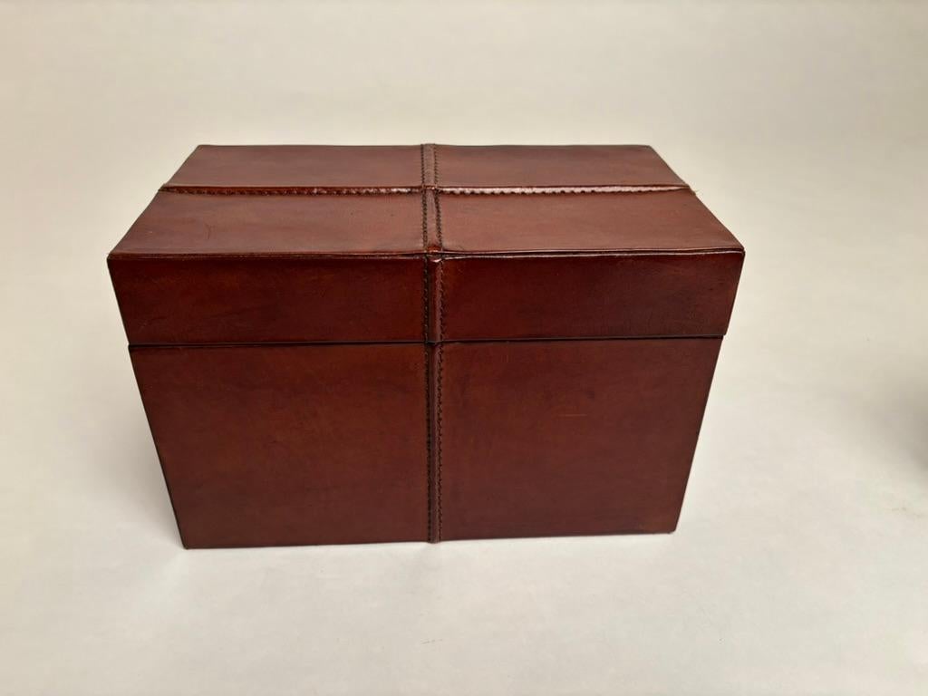 Elegant pair of mid century Italian leather wrapped boxes, rectangular in form with hand stitched raised bindings across the top and down the sides. Beautiful craftsmanship is evident on these handsome boxes. Nice chocolate patina. 
10.2 inches wide