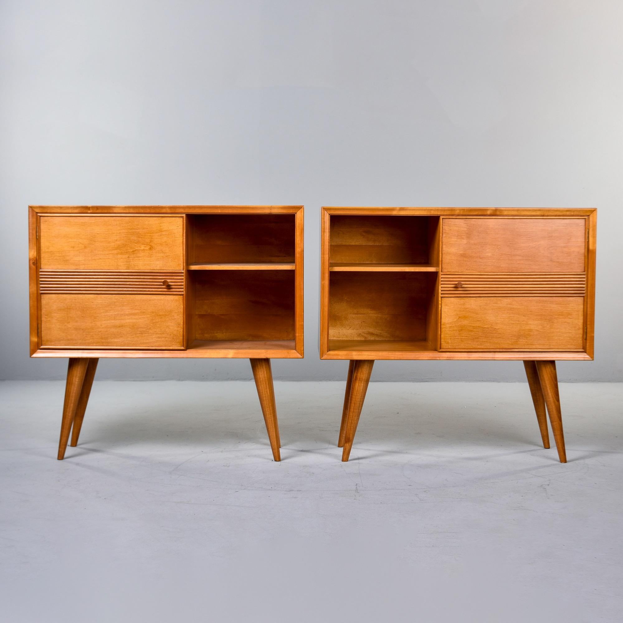 Found in Italy, this pair of ash wood side chests dates from the 1950s. Warm, medium blond in color, the cabinets each have an open compartment with a single fixed shelf and decorative carved banding on a hinged door that opens to interior storage