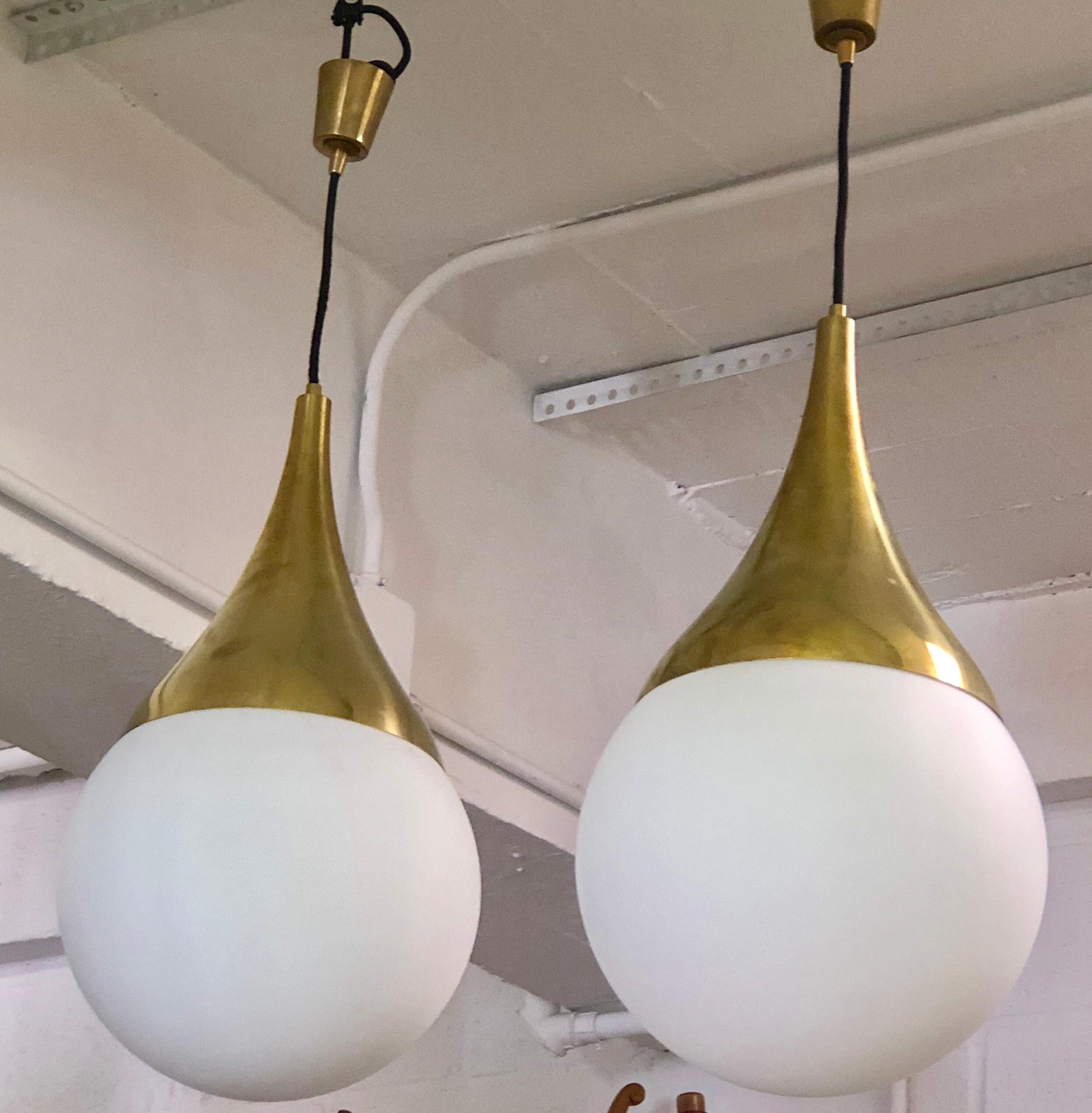 2 Rares pendentifs, lustres ou lanternes en laiton massif et verre opalin blanc soufflé par Max Ingrand pour Fontana Arte. Les pièces sont des chefs-d'œuvre de design aux formes intemporelles, élégamment conçues et exécutées avec des matériaux et un