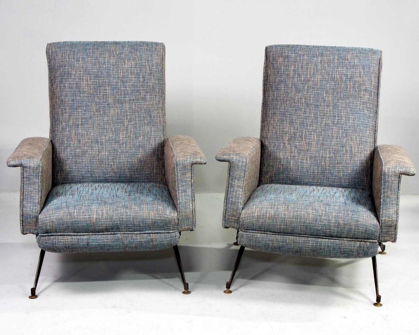Italian pair of reclining armchairs have been professionally upholstered in blue and taupe tweed fabric, circa 1950s. Chairs feature slender black metal legs, flat-topped arm rests and tall seat backs that recline. These chairs have a manual