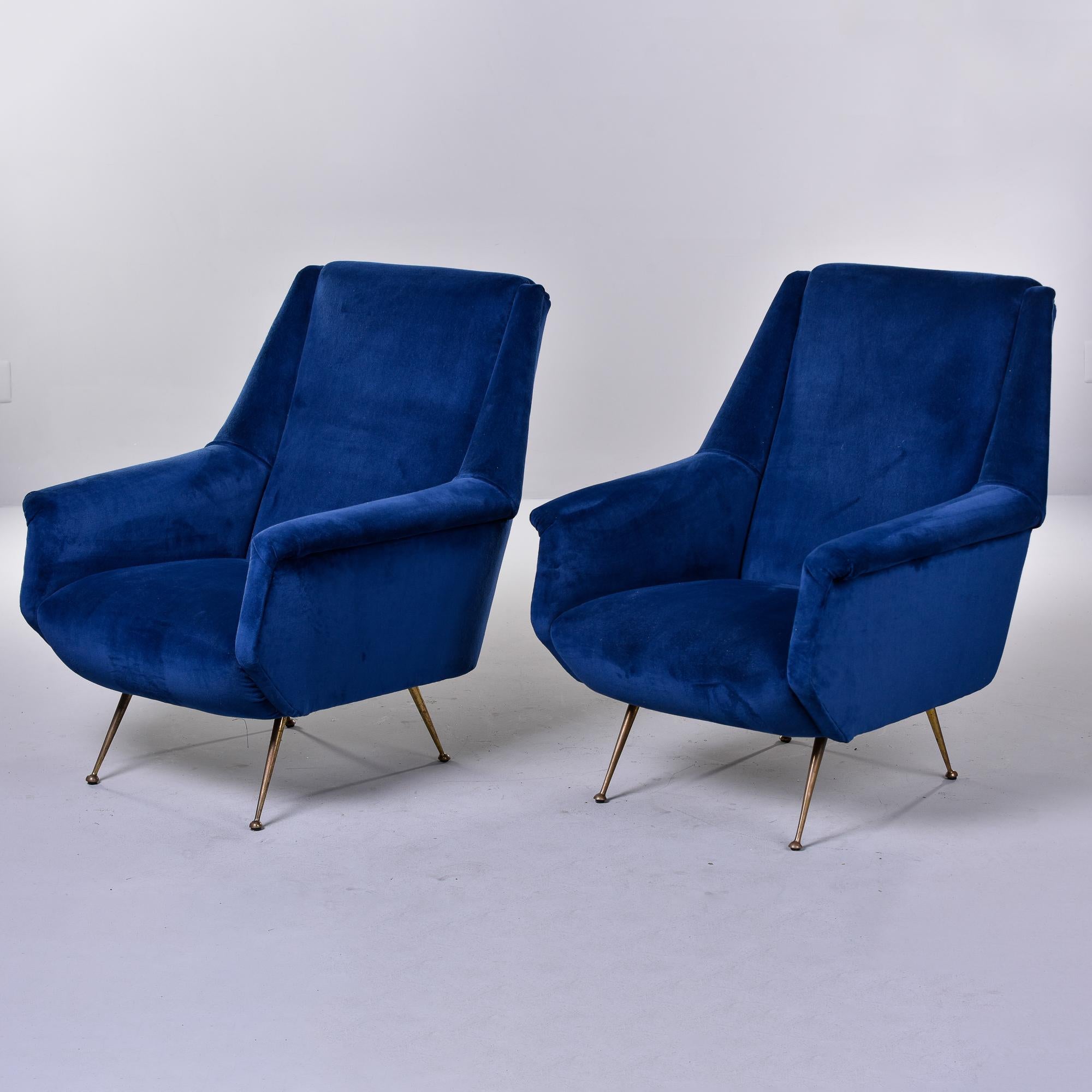 Found in Italy, this pair of circa 1950s sculptural arm chairs have narrow brass legs and new, deep blue velvet upholstery. Unlike many chairs from this era, these are generously proportioned with high backs. Unknown maker. Sold and priced as a