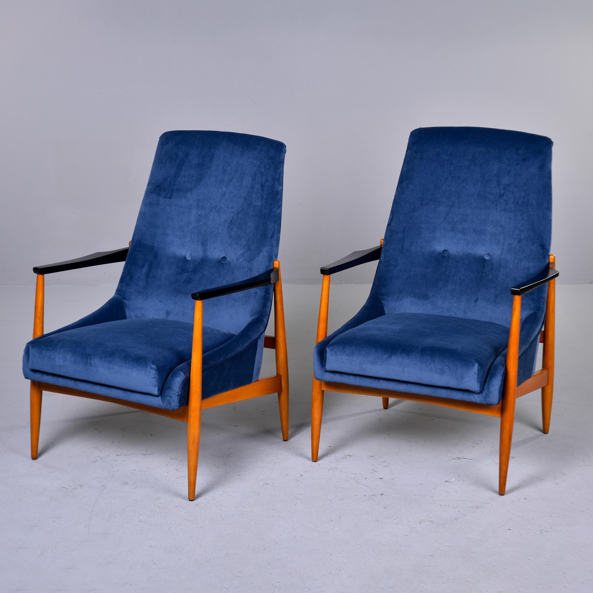 Found in Italy, this pair of circa 1960s lounge chairs feature slender teak frames with contrasting black arms. Seats are a modified scoop-form with two buttons on each tall seat back. The dealer we acquired the chairs from had them reupholstered in
