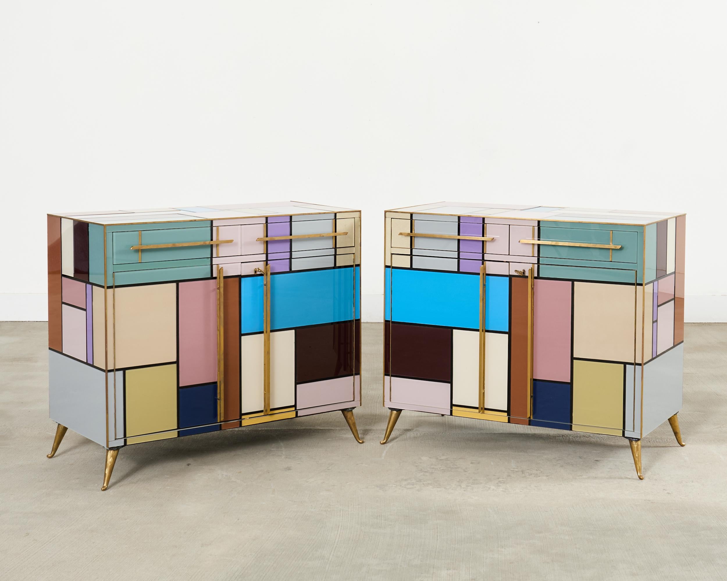 Sublime pair Italian mid-century modern colored glass and brass veneered cabinets inspired by the Dutch painter Piet Mondrian (Dutch 1872-1944). Fantastic mosaic of abstract geometric patterns in bright, vivid color or highlighted by sleek brass