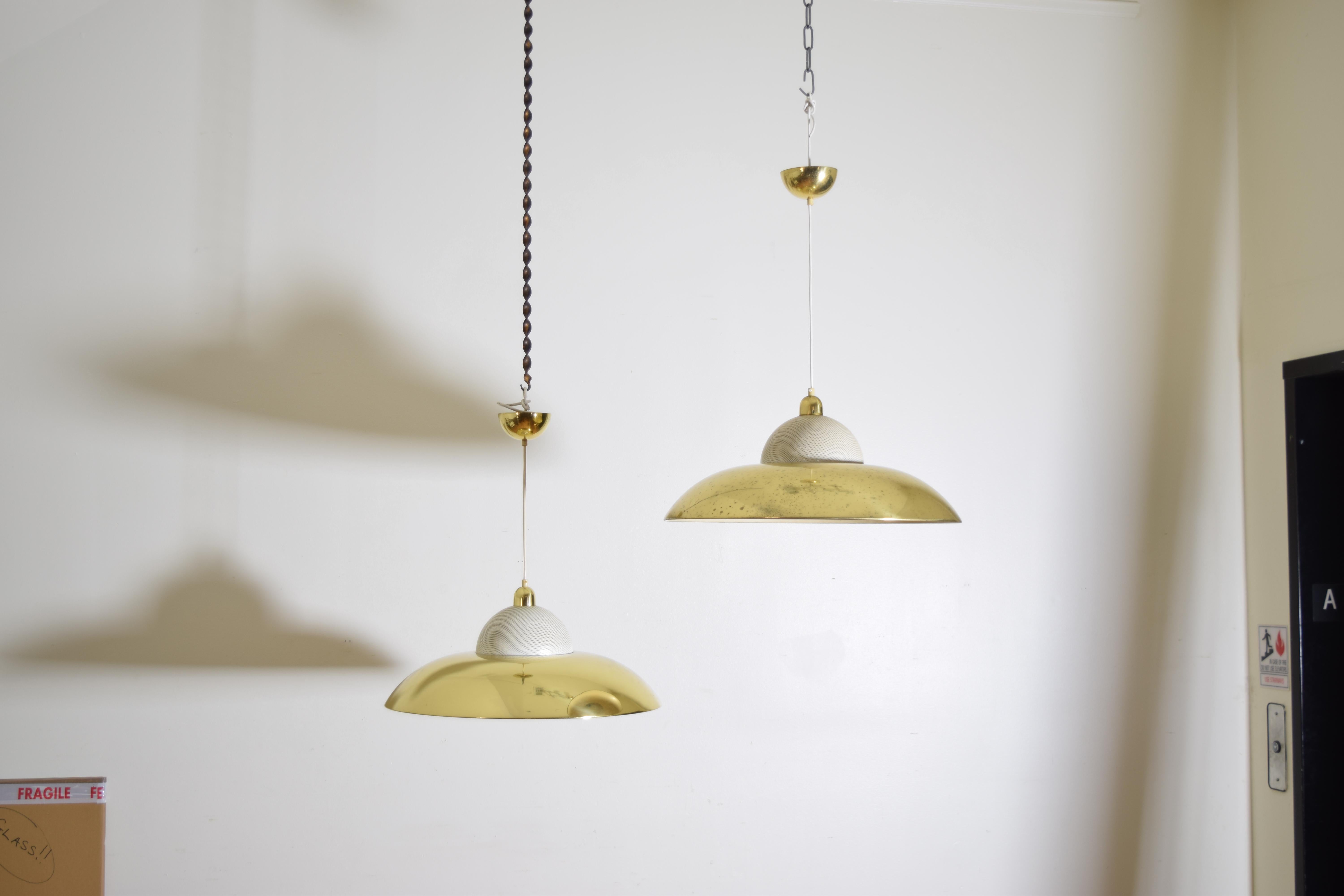 Each pendant with a large brass dome with a centered opening and an upper section of perforated and painted metal housing the down-light, retaining original brass canopies, the height completely adjustable depending on how much white cord is needed,