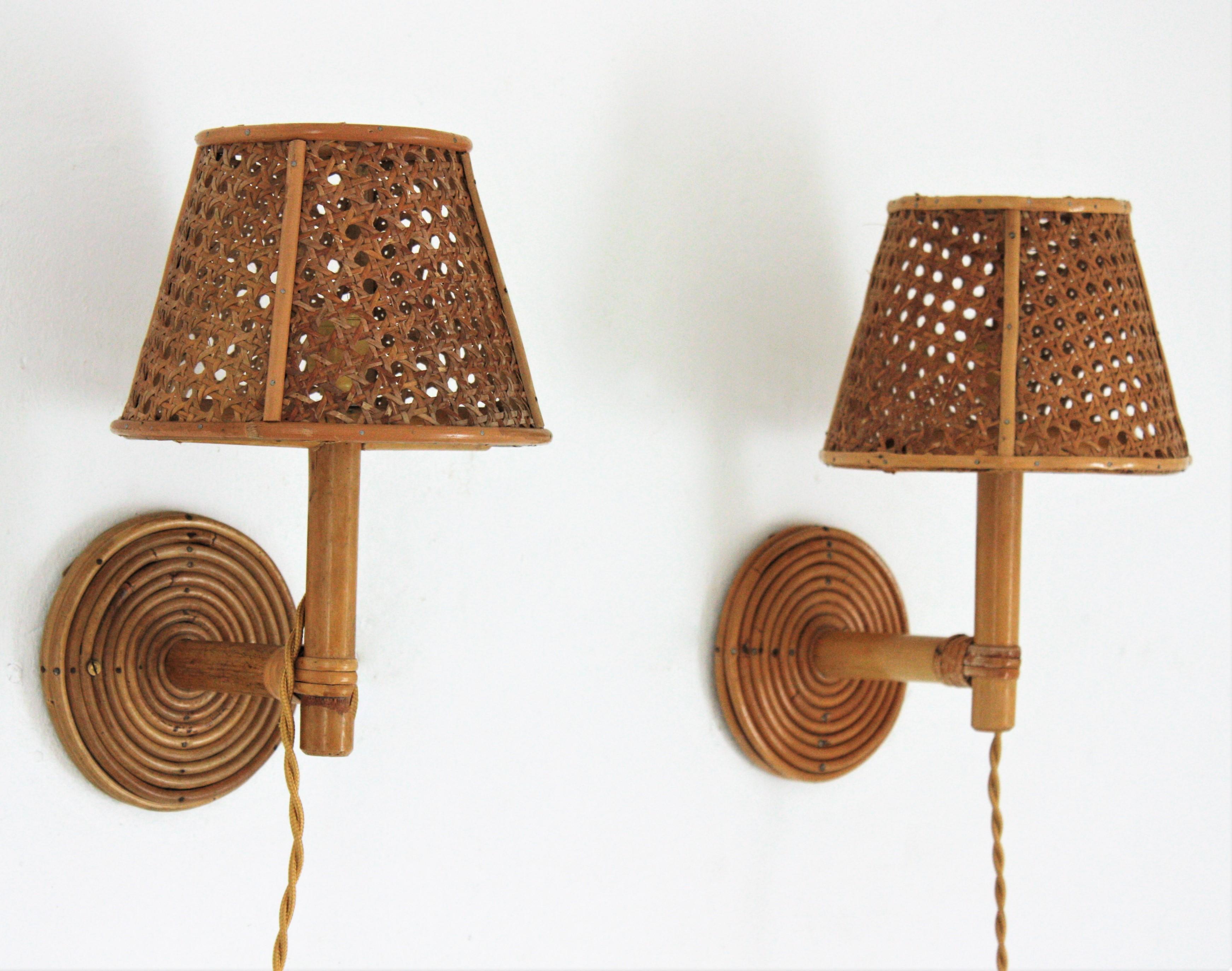 Eye-catching pair of Mid-Century Modern wicker and bamboo wall sconces with wicker weave shades: Italy, 1960s.
These wall lights feature round backplates covered with wicker holding bamboo arms with a wicker wire lampshades.
They will be the perfect