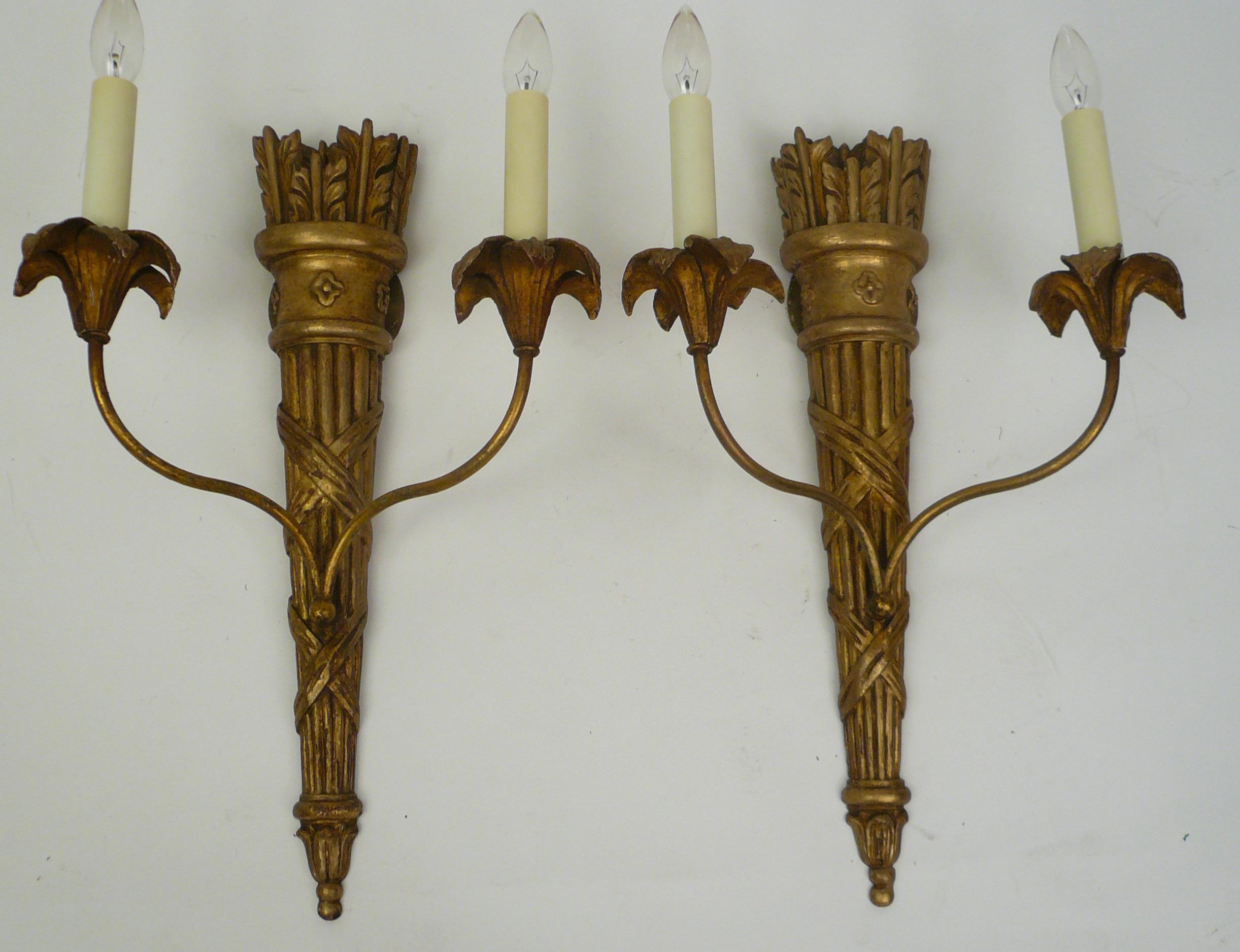 This pair of quiver form carved and giltwood sconces feature Classical motifs including reeding and rosettes.