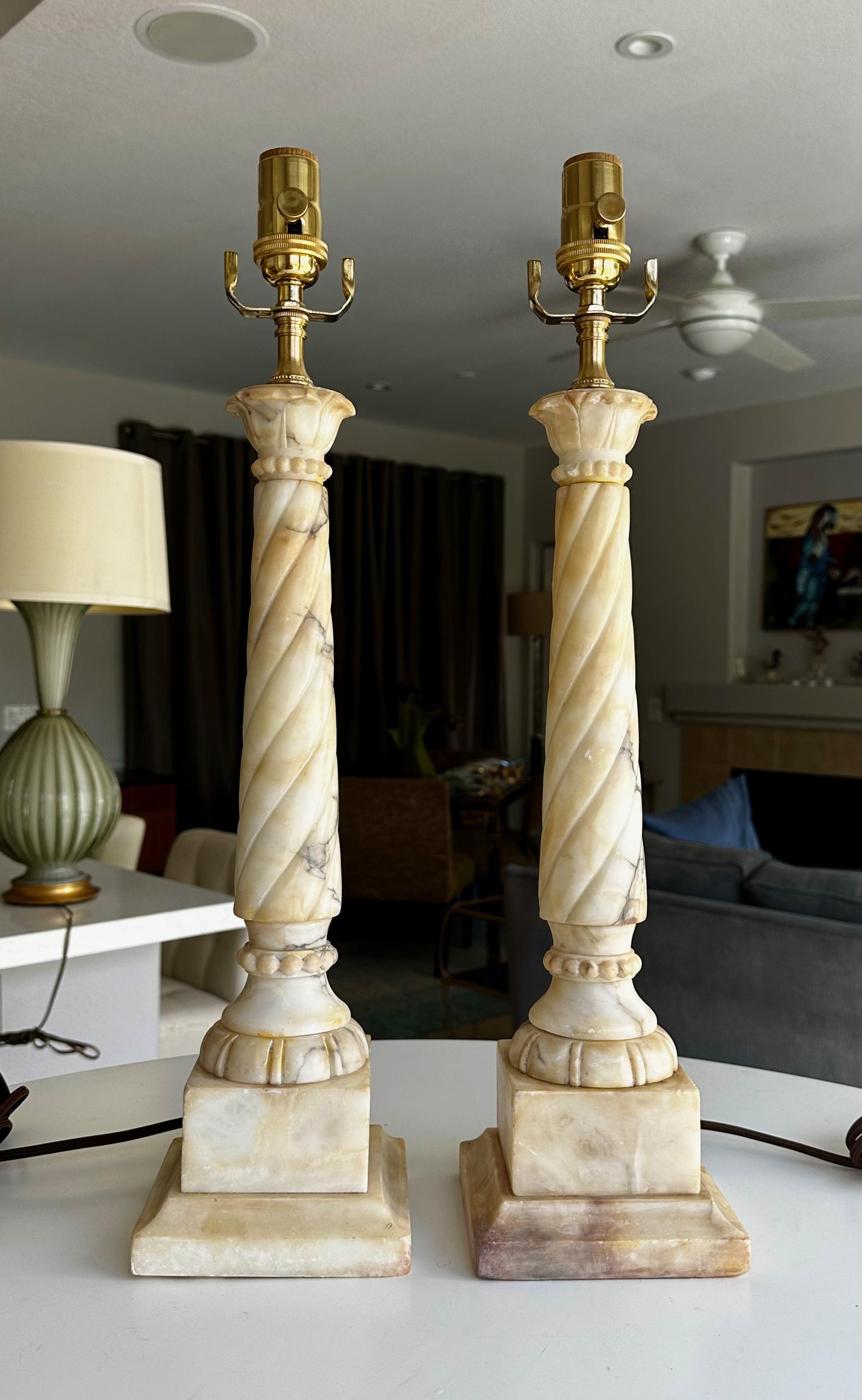 Pair of hand carved neoclassic style twisted column theme alabaster lamps. The alabaster has yellow and brown highlights throughout see close ups. Newly wired with 3 way brass sockets and rayon covered corded cords.

.