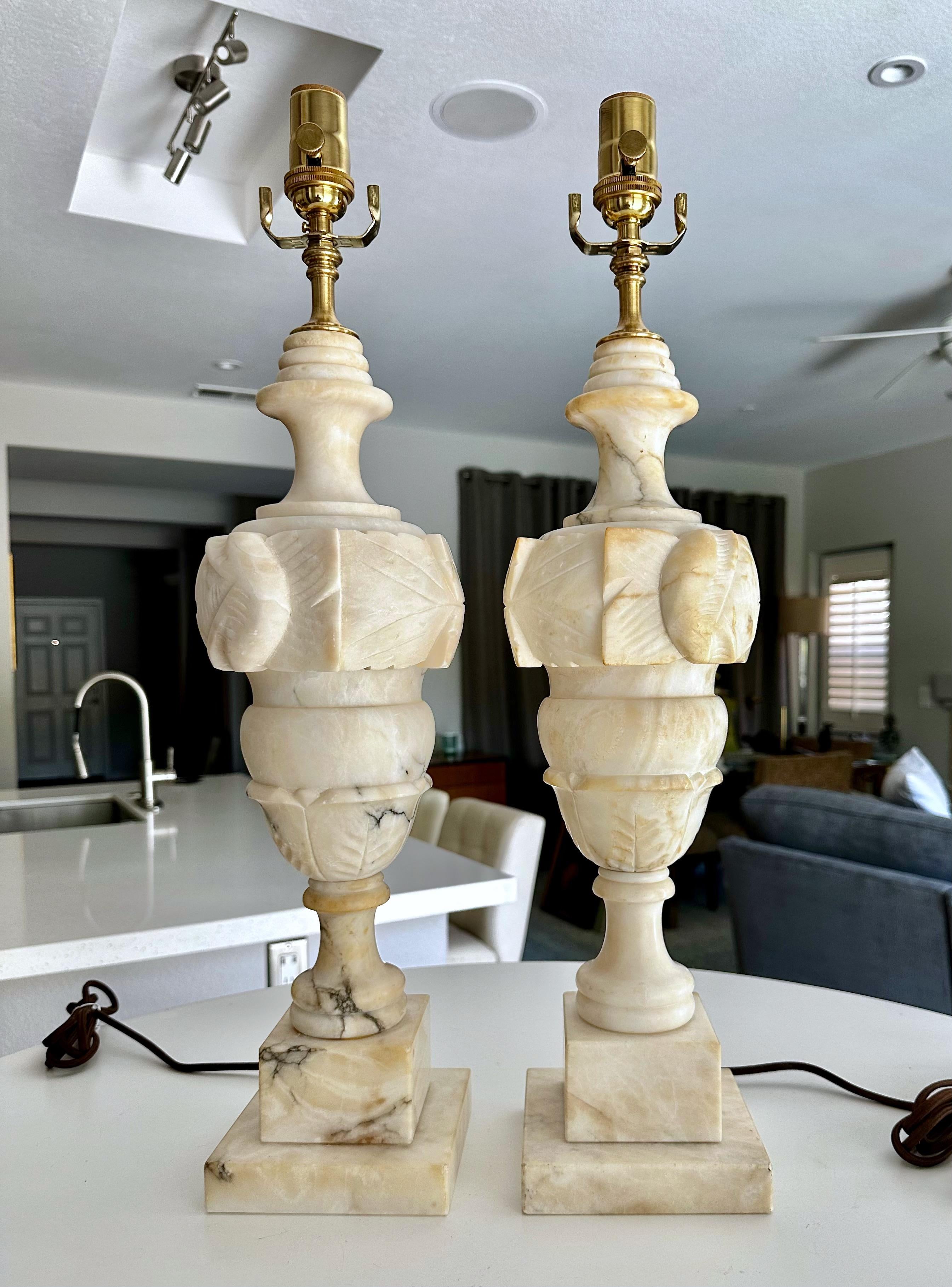 Pair of large finely crafted hand carved neo-classic style urn form alabaster lamps. The intricately carved white alabaster are covered with lots natural colorful veining. Newly wired with 3 way sockets and rayon covered cords.
Shades not included.
