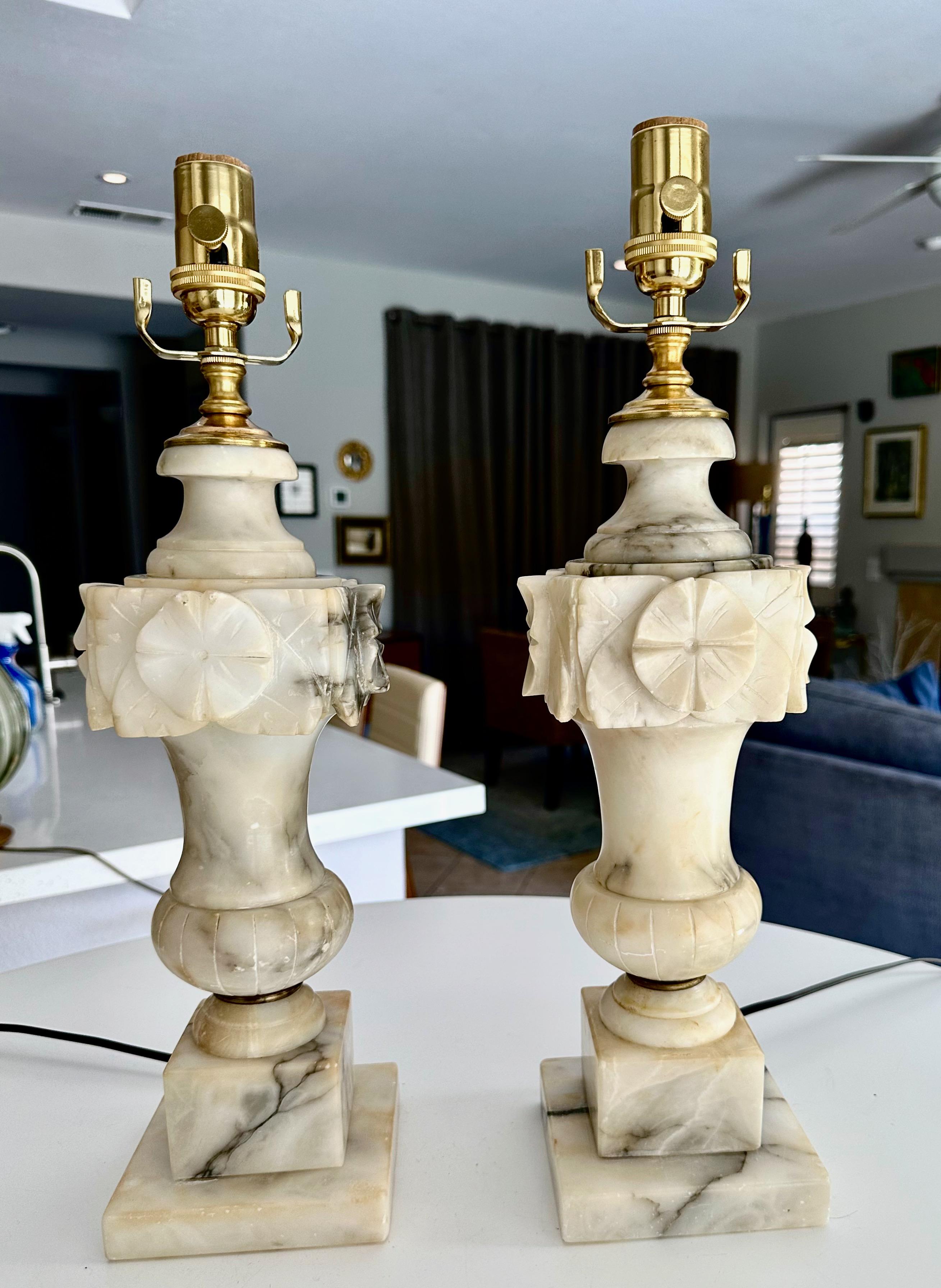 Pair of large finely crafted hand carved neo-classic style urn form alabaster lamps. The intricately carved white alabaster are covered with lots natural colorful veining.  Newly wired with 3 way sockets and cords.
Overall height top of socket