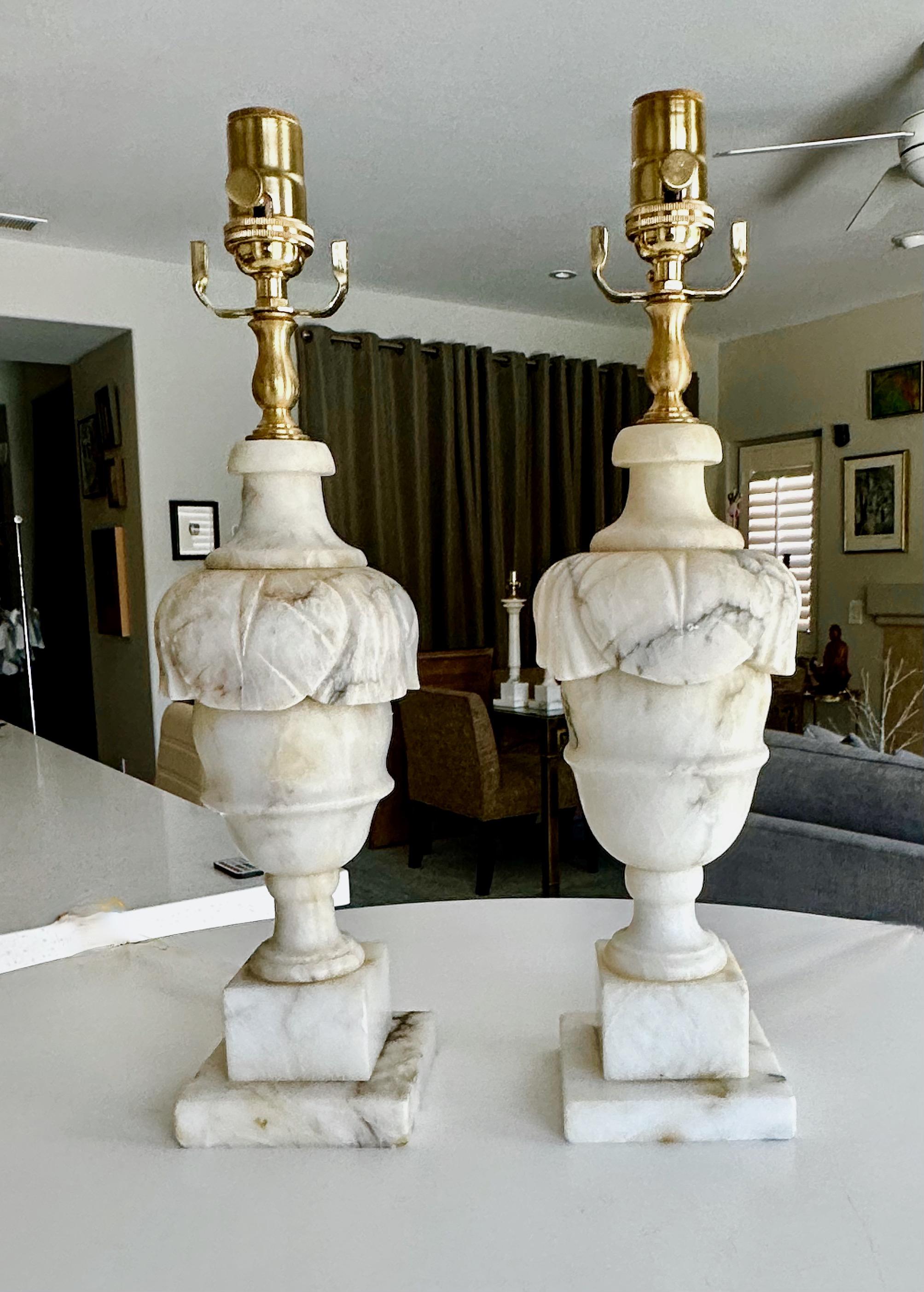 Pair of finely crafted hand carved neo-classic style urn form alabaster lamps. The intricately carved white alabaster are covered with lots natural colorful veining.  Newly wired with 3 way sockets and cords.
Overall height top of socket 18