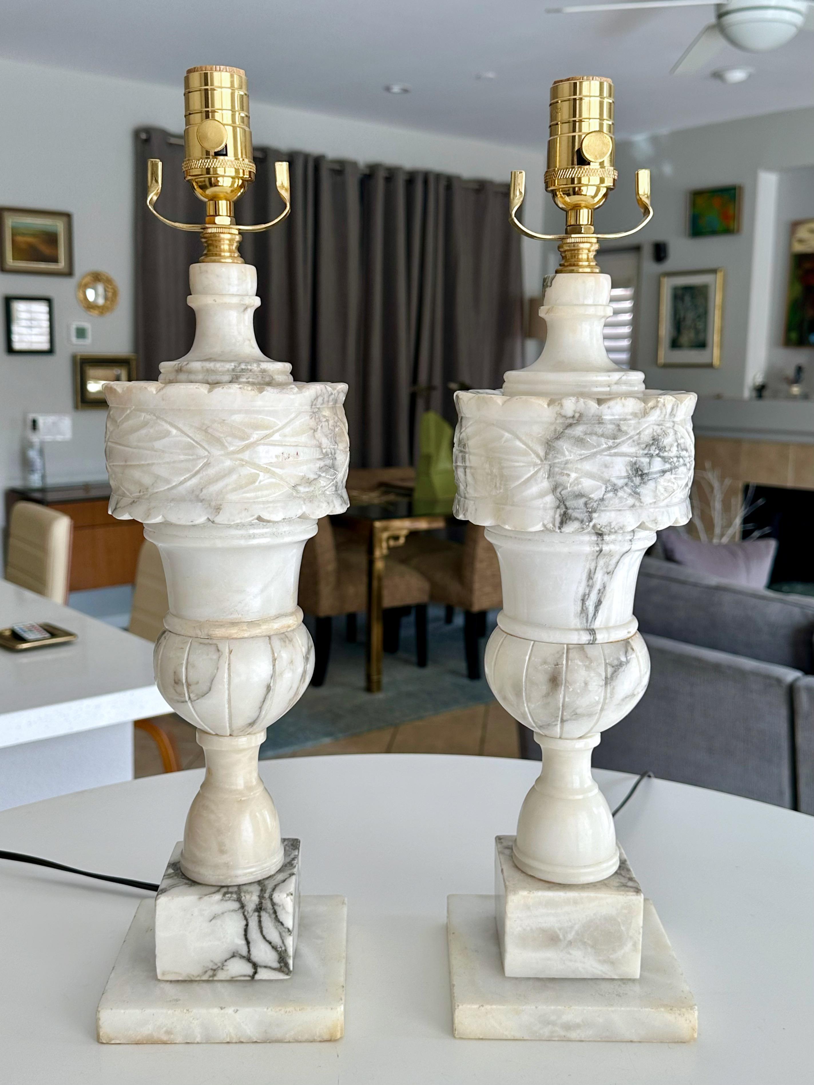 Paire de lampes en albâtre de style néo-classique finement sculptées à la main en forme d'urne. L'albâtre blanc sculpté de manière complexe a  beaucoup de veines naturelles colorées.  
Hauteur totale du sommet de la douille 20