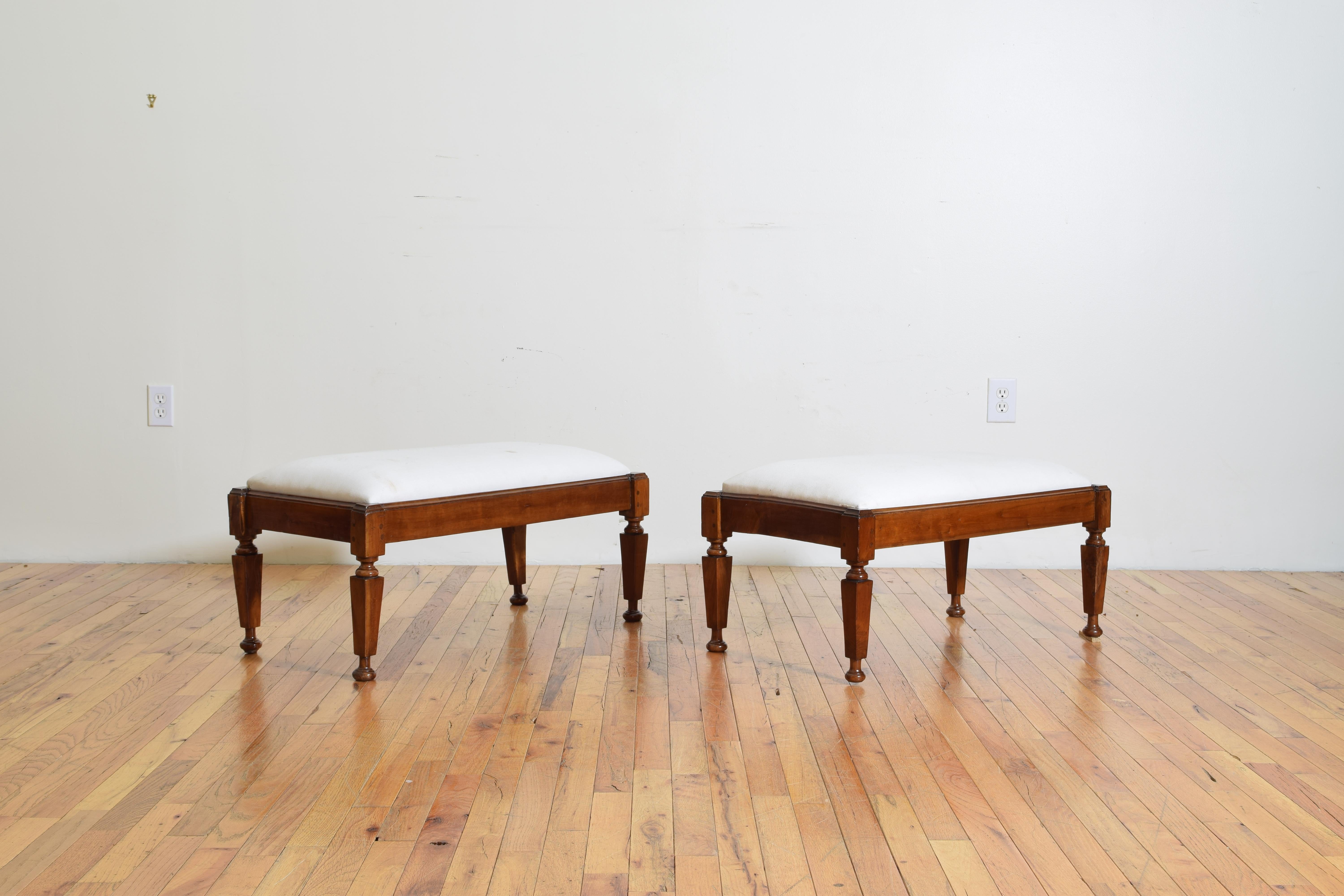 The benches having removable upholstered seats, the rectangular frames with notched corners with turned and tapering block legs terminating in bun feet, first quarter of the 19th century.