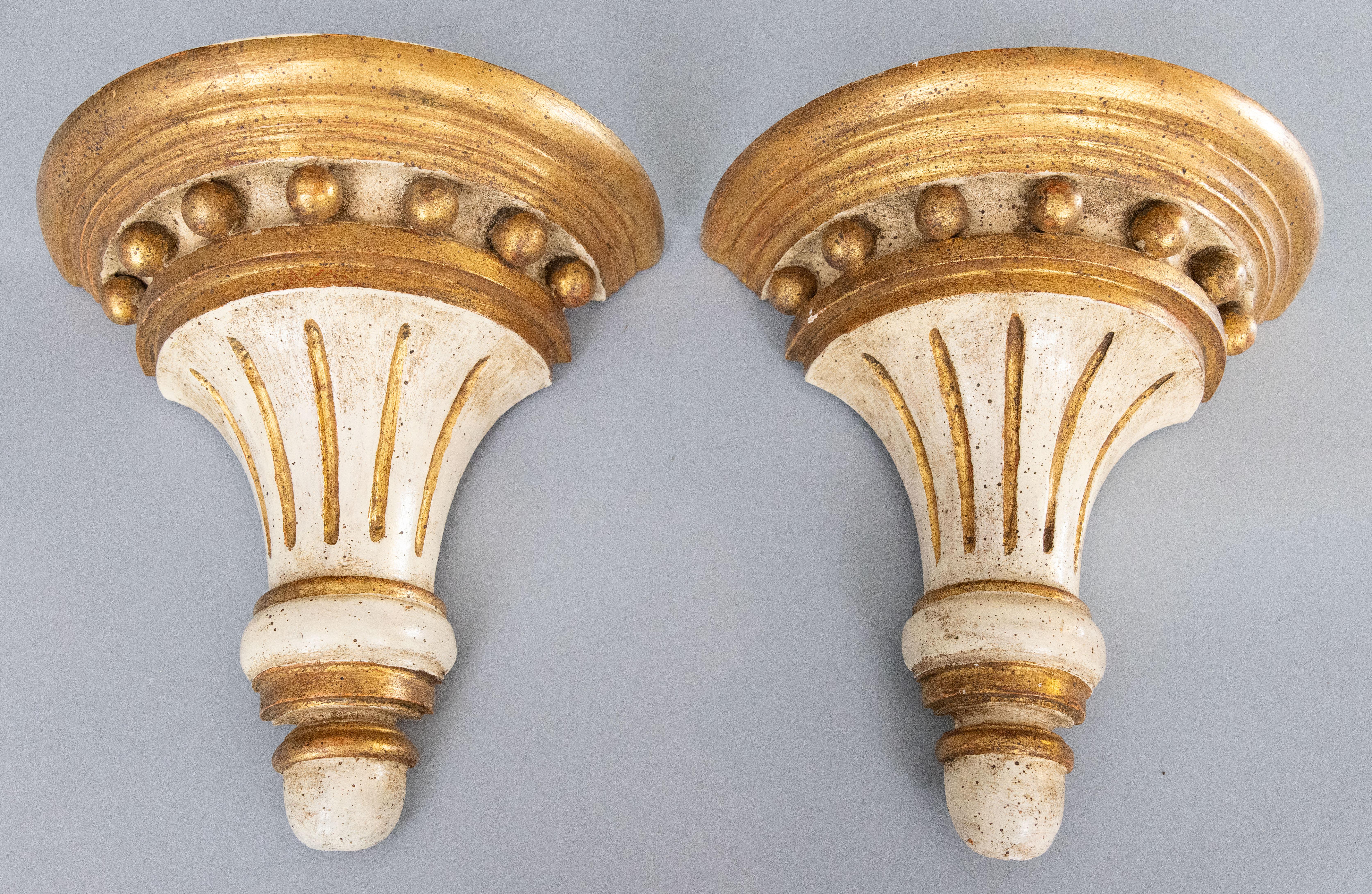 Magnifique paire de consoles murales ou de corbeaux en bois doré de style néoclassique italien, d'une belle patine, vers 1950. Ces supports élégants présentent un joli design cannelé blanc vieilli et doré avec des sphères dorées, parfait pour la