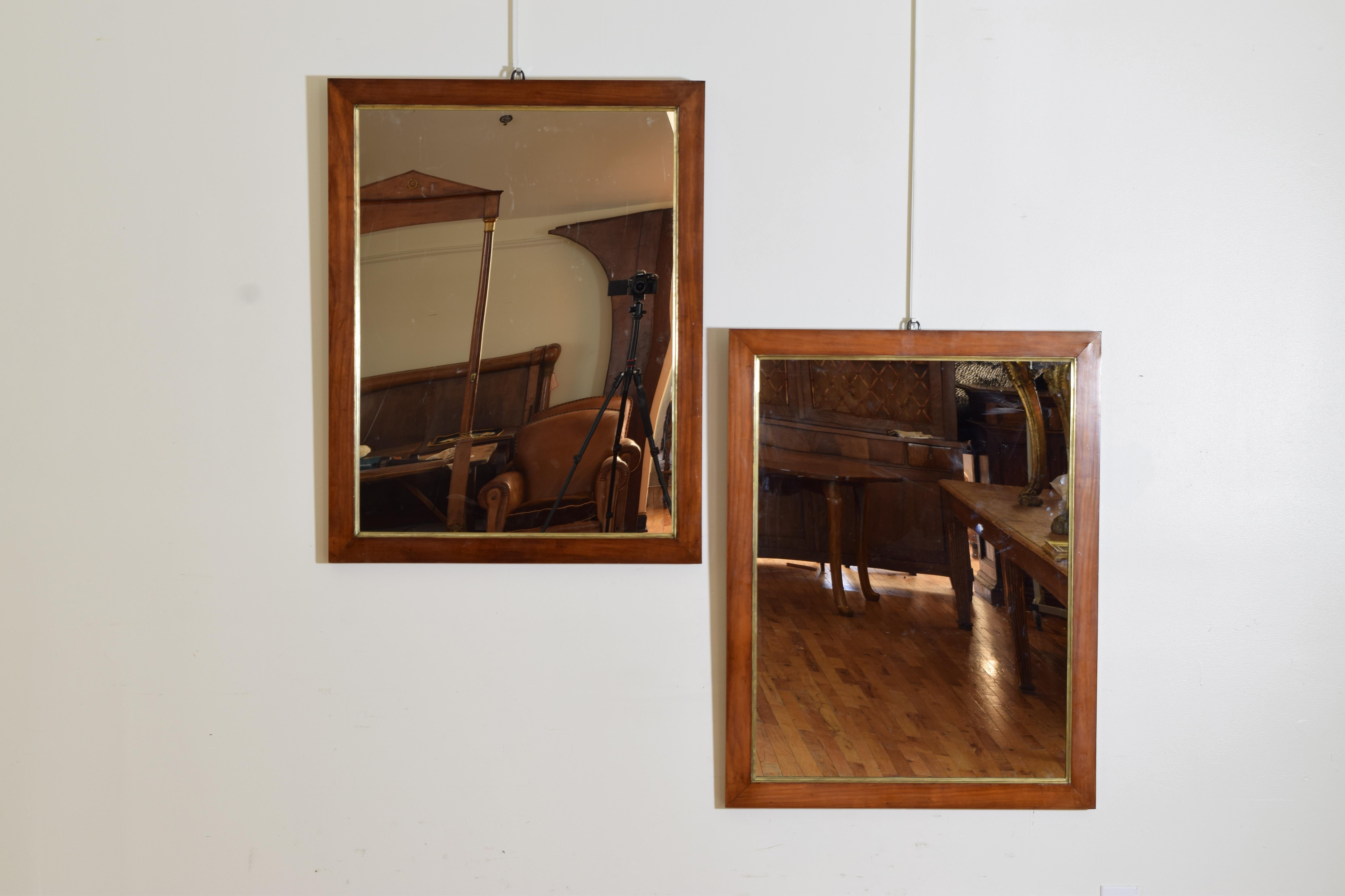 Each rectangular frame covered in walnut veneer with an interior shaped brass molding, with new mirrorplates 