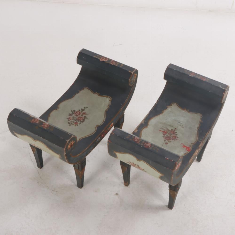 A pair pf Italian paint decorated Roman style wood benches C 1940, a variation of the curule form, each with curved seats painted with flowers within gilt cartouches supported by 4 legs. Curule is defined as a something relating to the authority of