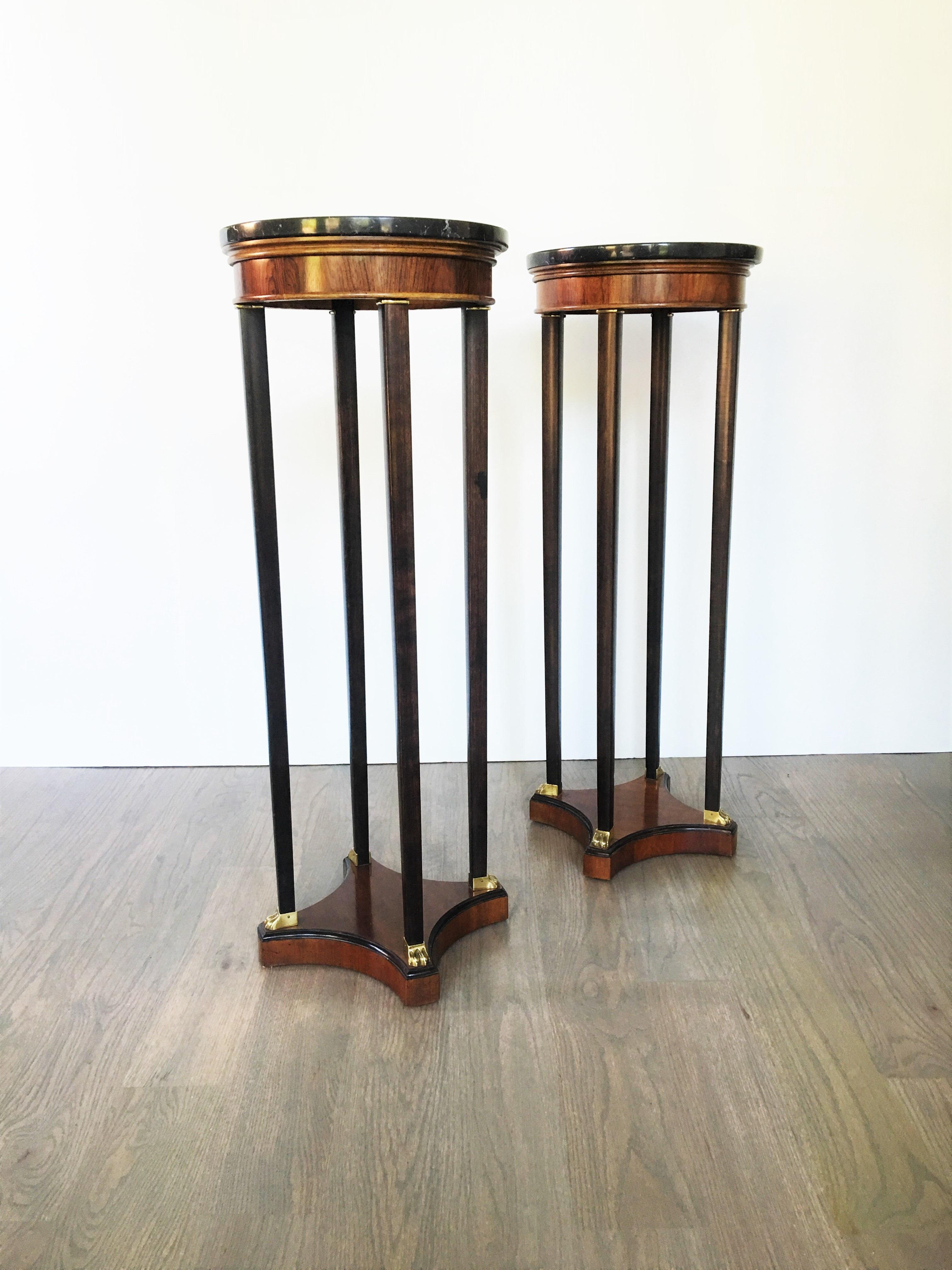 An outstanding pair of classically shaped tall plant stands or display pedestals. Done in a gorgeous rose wood with complimenting ebonized legs. Each pedestal consists of a beautiful circular marble top with a nice rosewood apron below. The long,