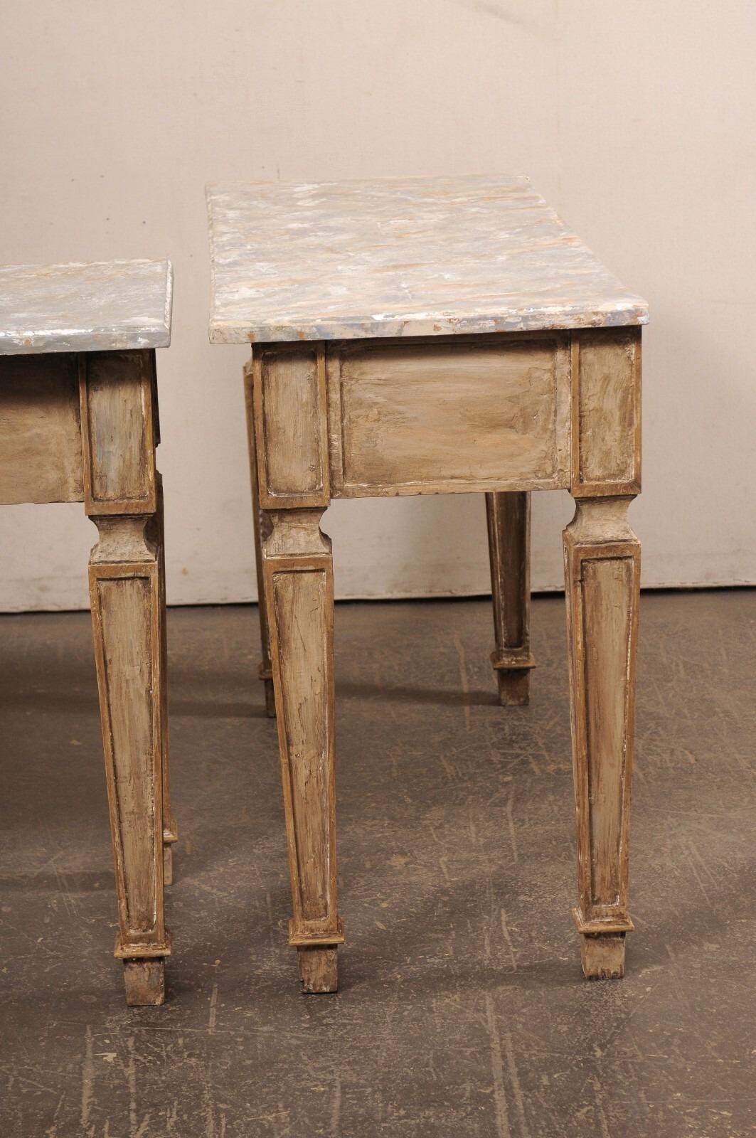 Pareja vintage de consolas de madera tallada y pintada, con tapa de imitación de mármol. Estas mesas de American han sido diseñadas con influencias italianas, y cada una tiene un tablero de forma rectangular y de imitación al mármol, que sobresale