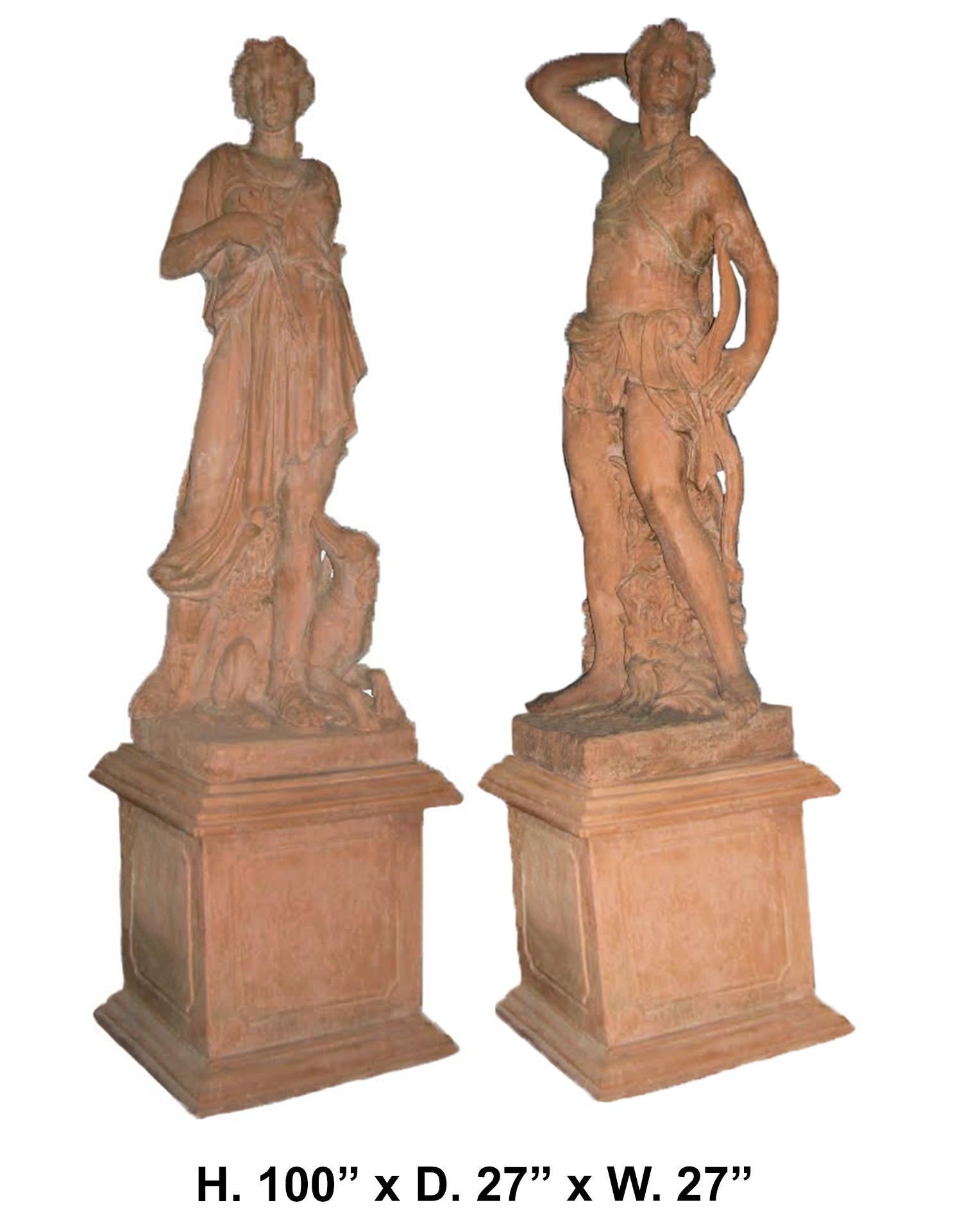 Outstanding monumental pair of Italian terracotta garden statues.
The life-size terracotta maiden is standing dressed with neoclassical robes near a dog. The male hunter wields a bow and quiver behind his right shoulder standing in front of a