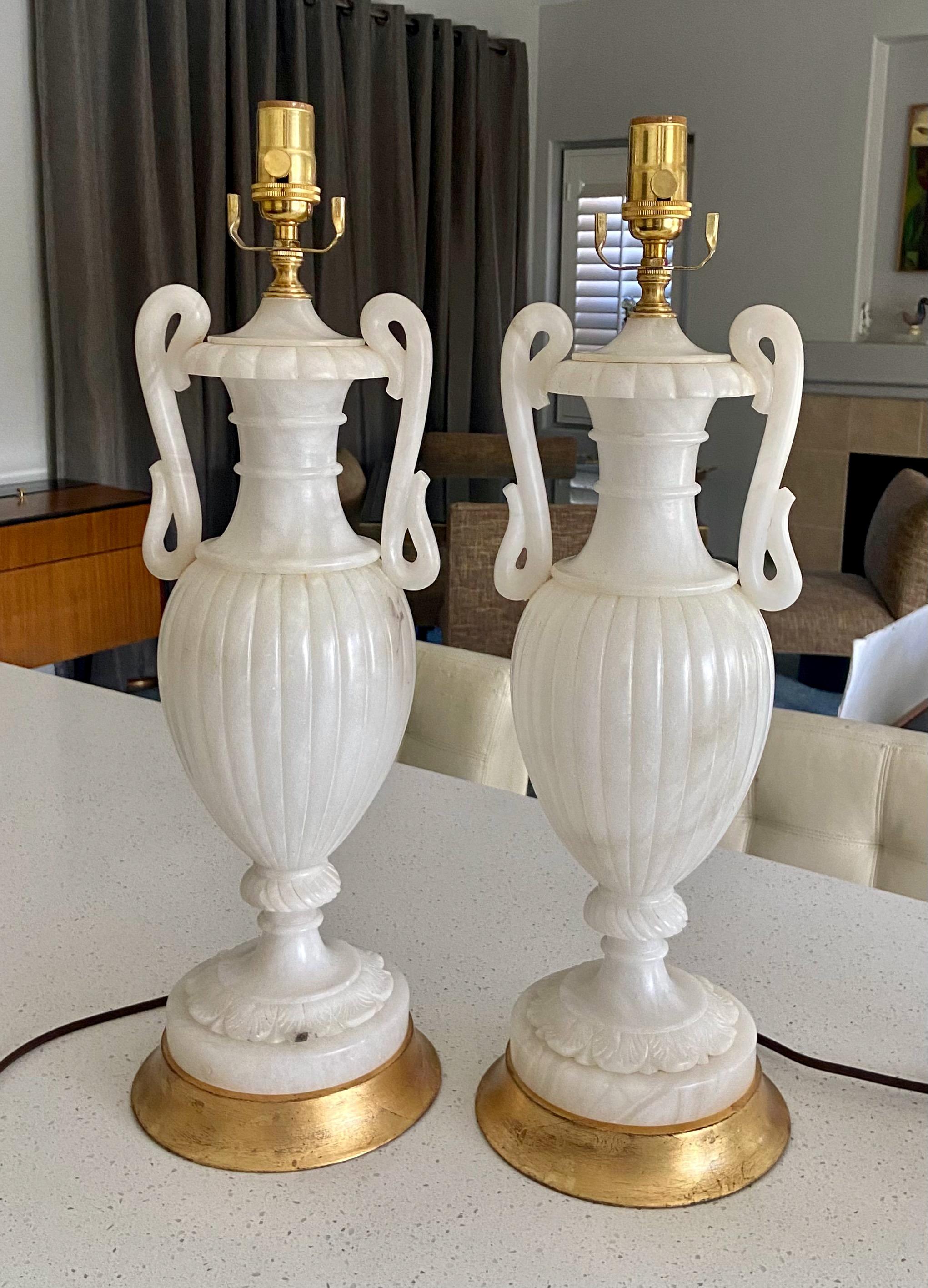 Exceptional pair of neoclassical style carved urn form with handles alabaster table lamps. Expertly carved throughout with custom giltwood bases. Newly wired with new brass 3 way sockets and rayon cords. 
Measures: Size of the alabaster alone 18