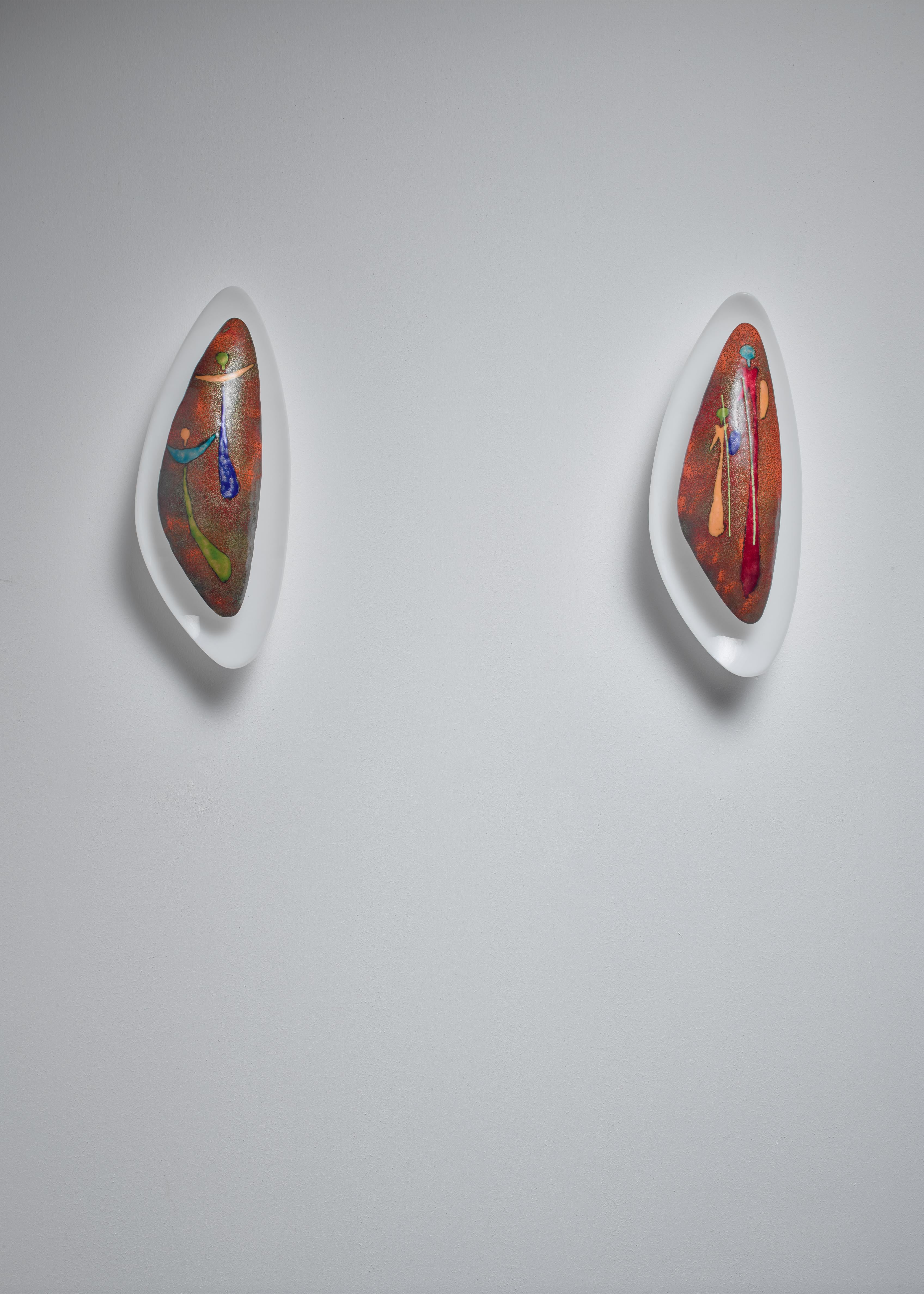 Two handmade Italian wall lamps made out of an old plastic wall-mount and an enameled metal, multicolored shade. The shades show two biblical images from the nativity story: two angels and two of the Kings.