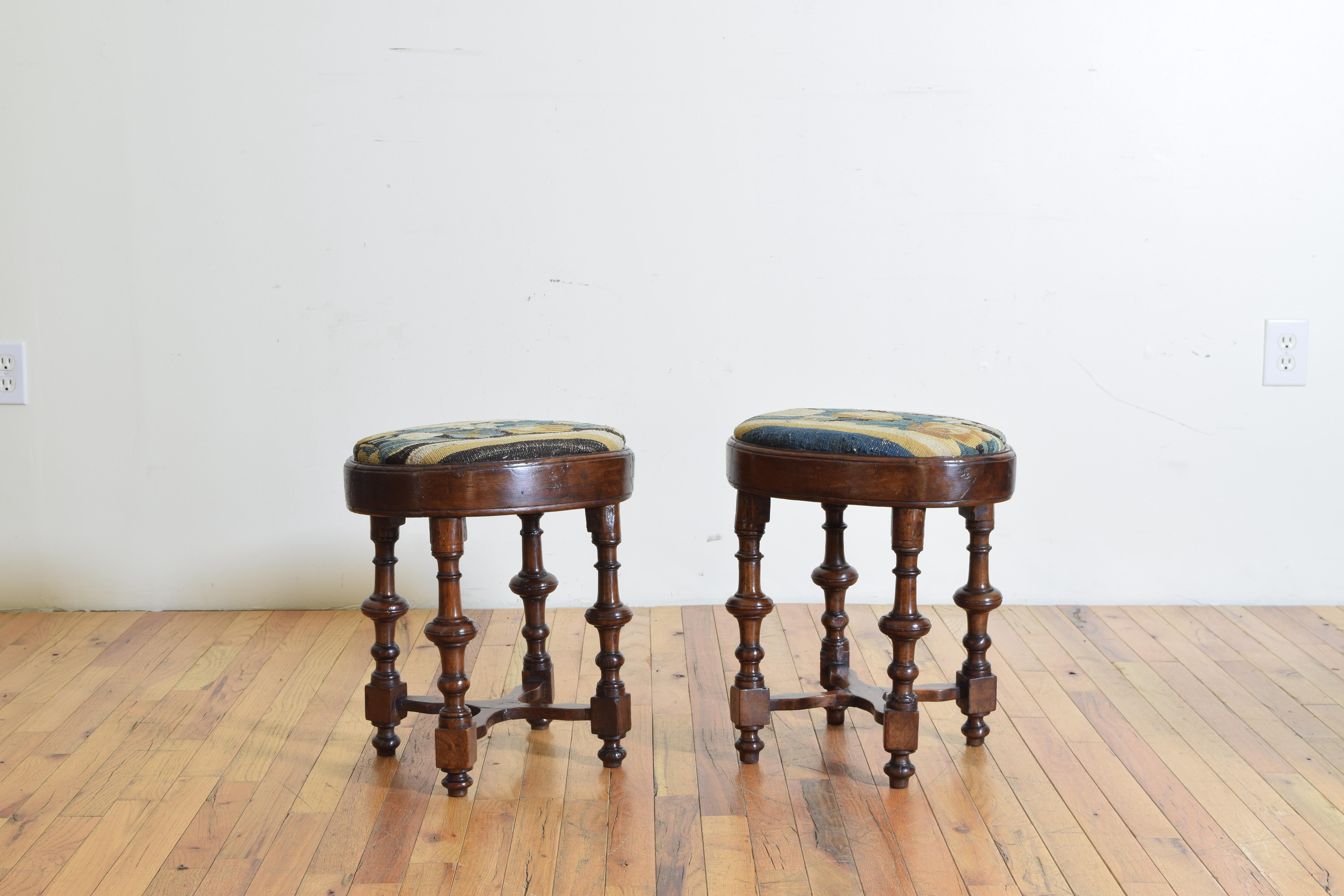 Likely Tuscan in origin these stools have oval shaped tops with drop in tapestry upholstered seats, raised on turned and block legs joined by X-form stretchers.