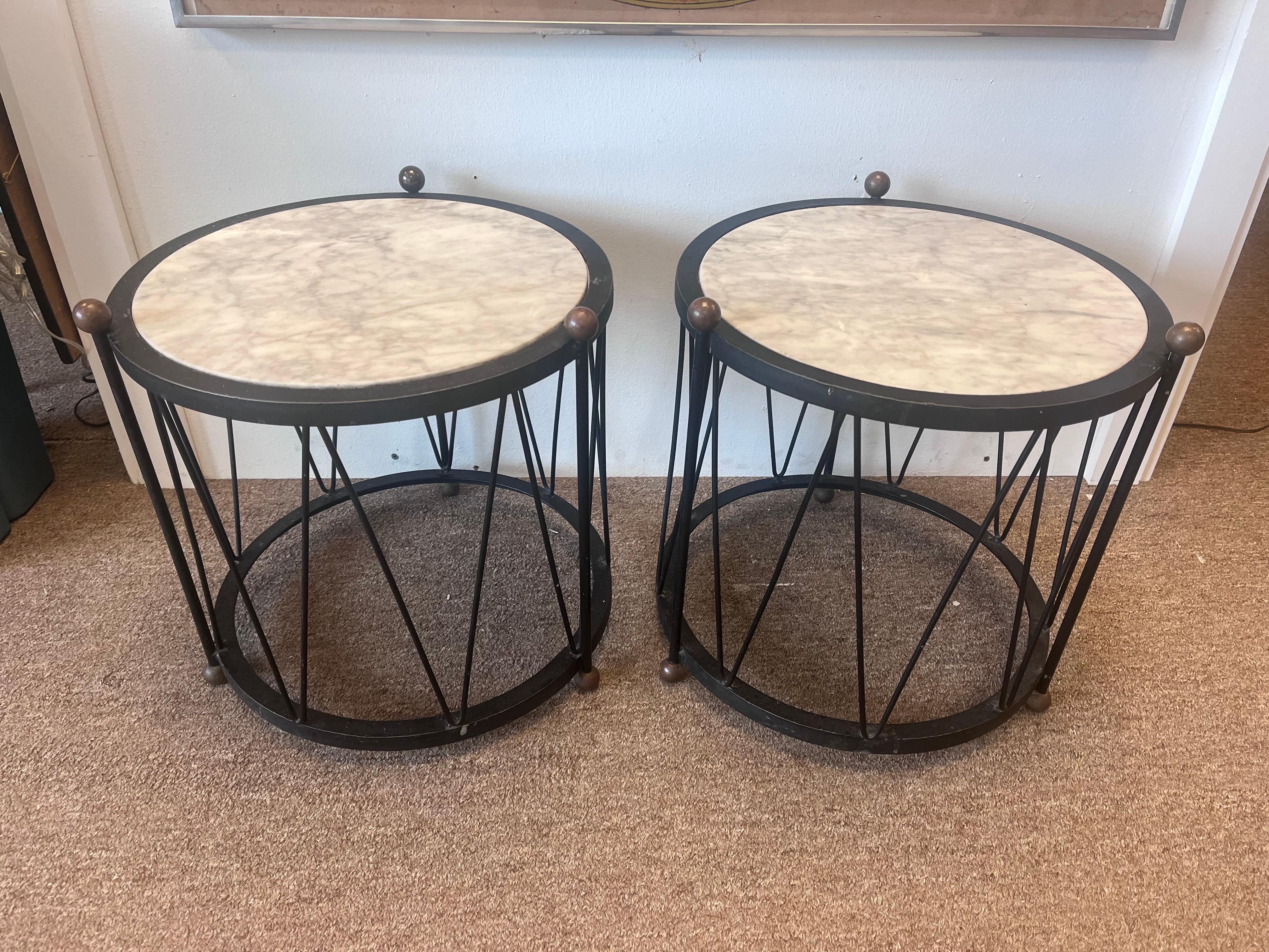 A pair of mid 20th century Italian marble and iron drum tables. The pair of tables features a thick, round white marble insert that is marked ITALY on the underside. The black iron bases have a wide banded rim and foot on the top and bottom as well