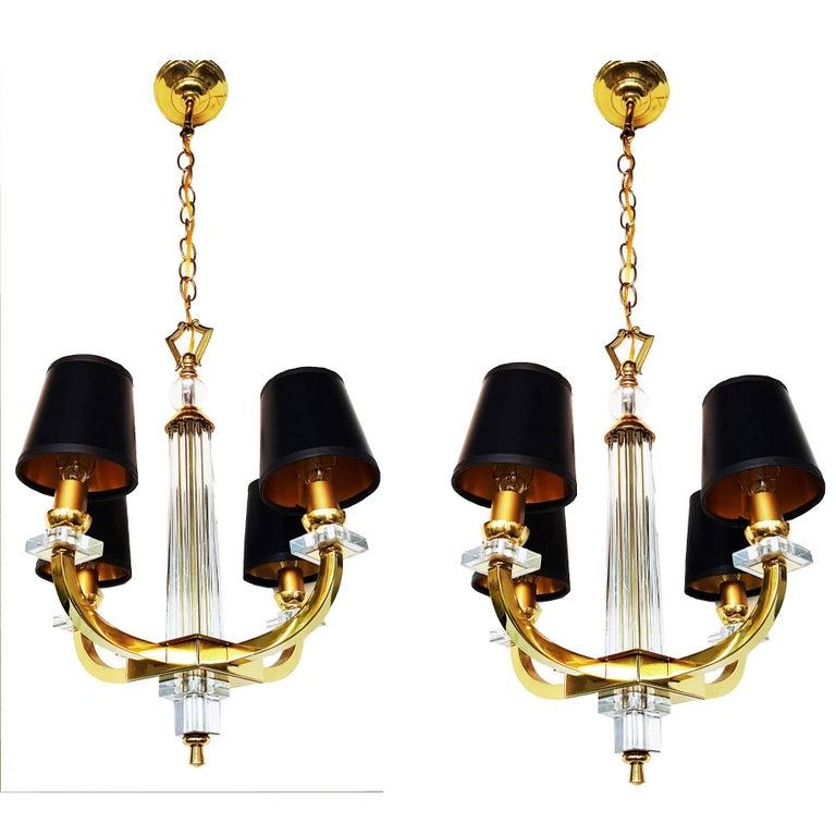 Pair of Jacques Adnet Style designed 4 Light chandelier of brass, Lucite and blown glass rods made by Maison Jansen. 
Very chic with the combination of Glass elements and Brass details. 
The shades in black or off-white are included. You