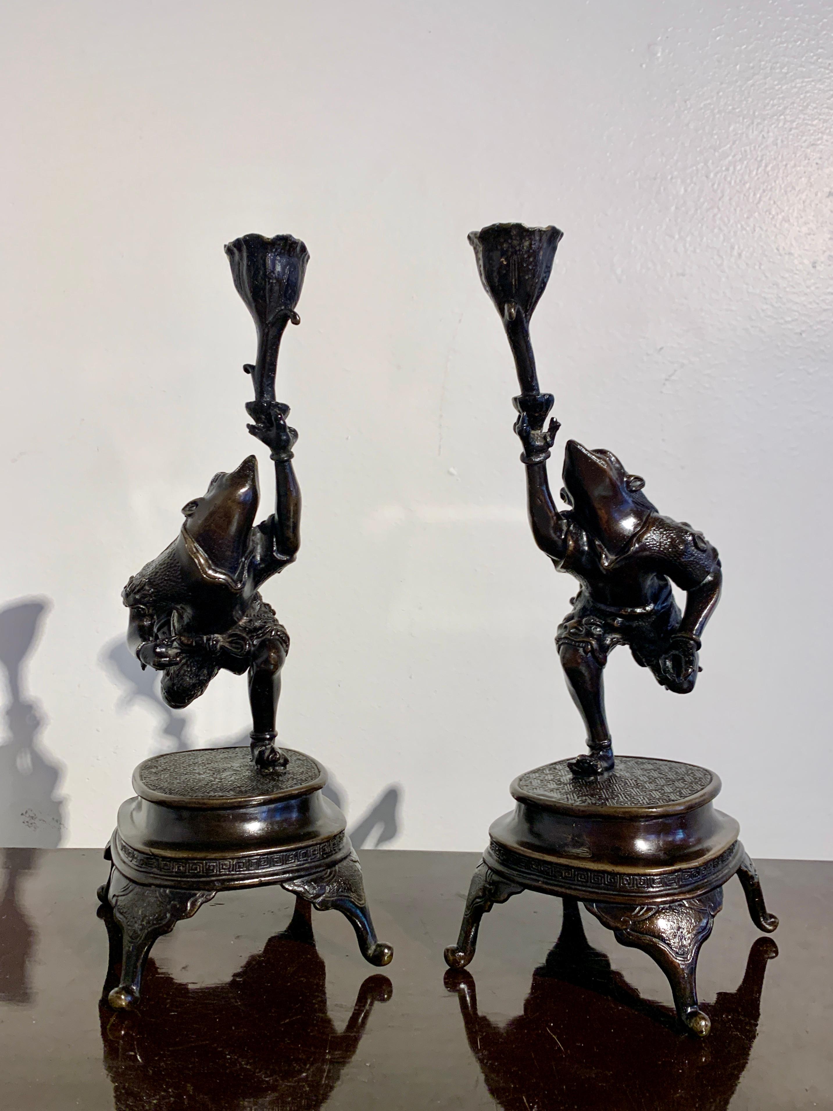 A fantastic and fabulous pair of Japanese cast bronze candlesticks in the form of armored frog warriors, Meiji Period, circa 1900, Japan.

The delightful mirrored pair of bronze candleholders modeled as warrior frogs wearing armor. The frogs