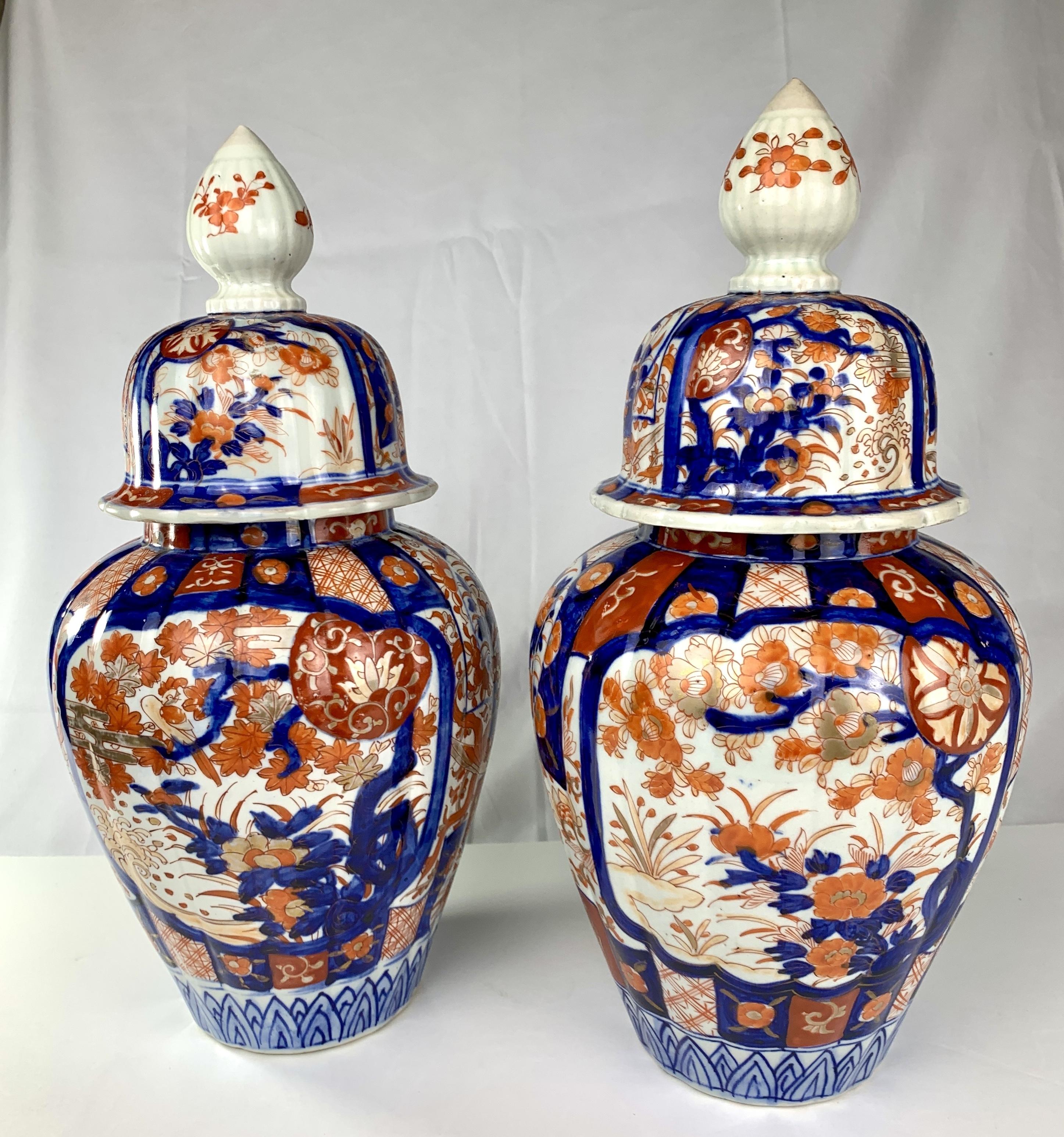 Hand-painted in Imari designs, both jars show beautiful waterside scenes in cobalt blue, gilt, and two tones of iron red. 
The colors are exquisite and intense. We see water lilies, lotus, peonies, and bellflowers.  One jar shows a shoreline the